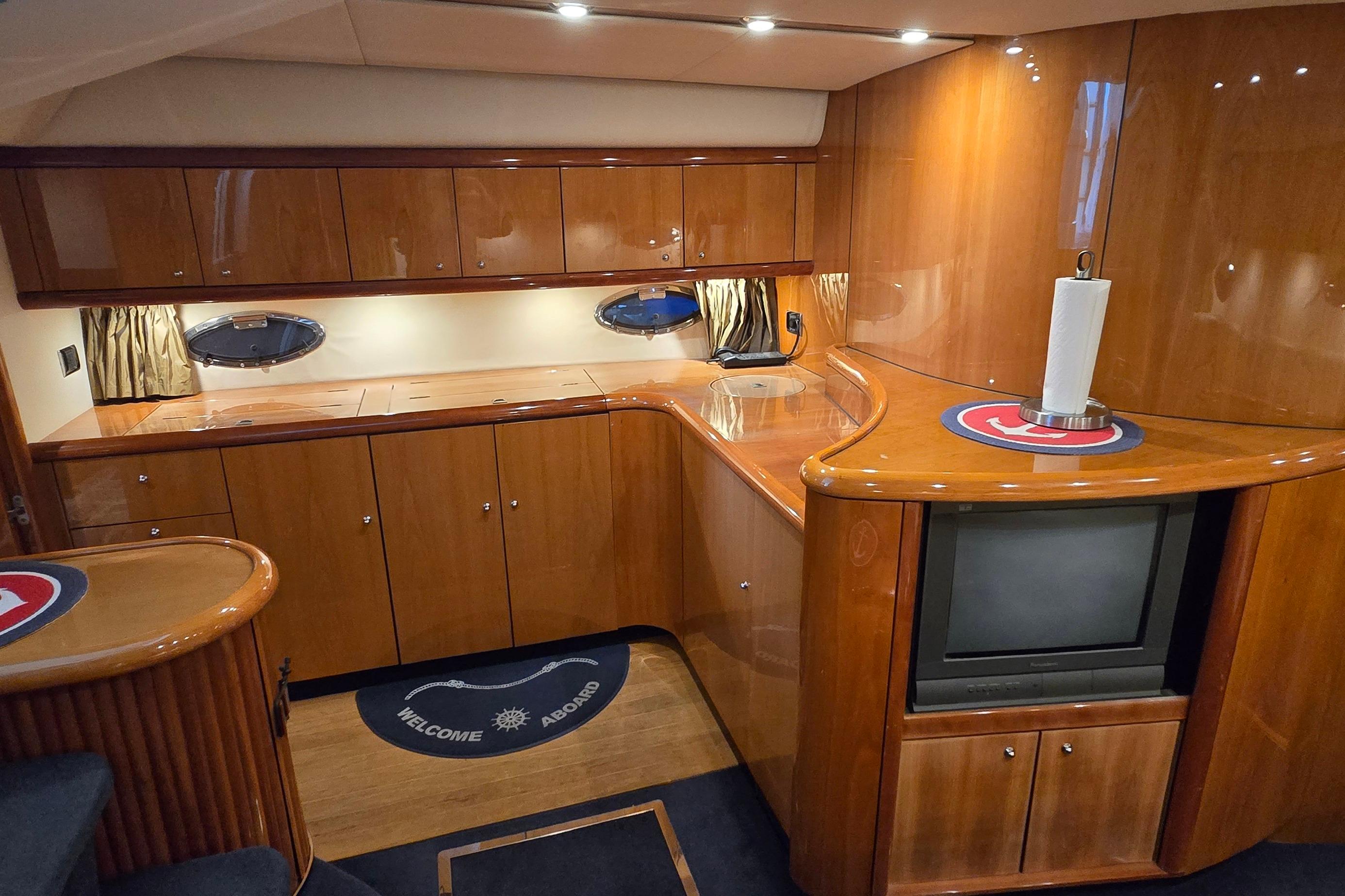 Luxurious 2004 Sunseeker Camargue 50 yacht interior with polished wood cabinetry and modern amenities.