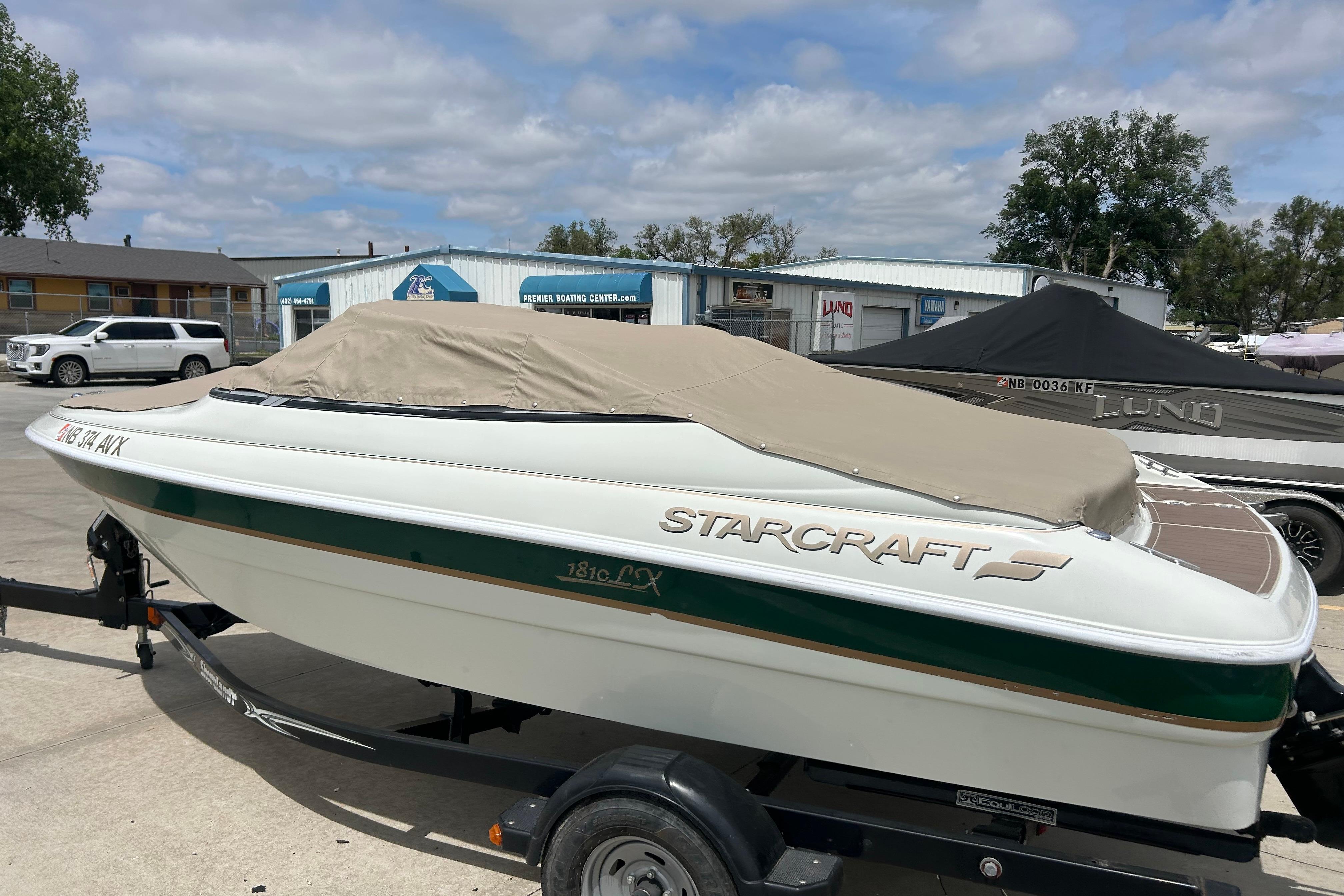 2000 Starcraft 1810 boat with cover on trailer, parked outdoors under cloudy sky.