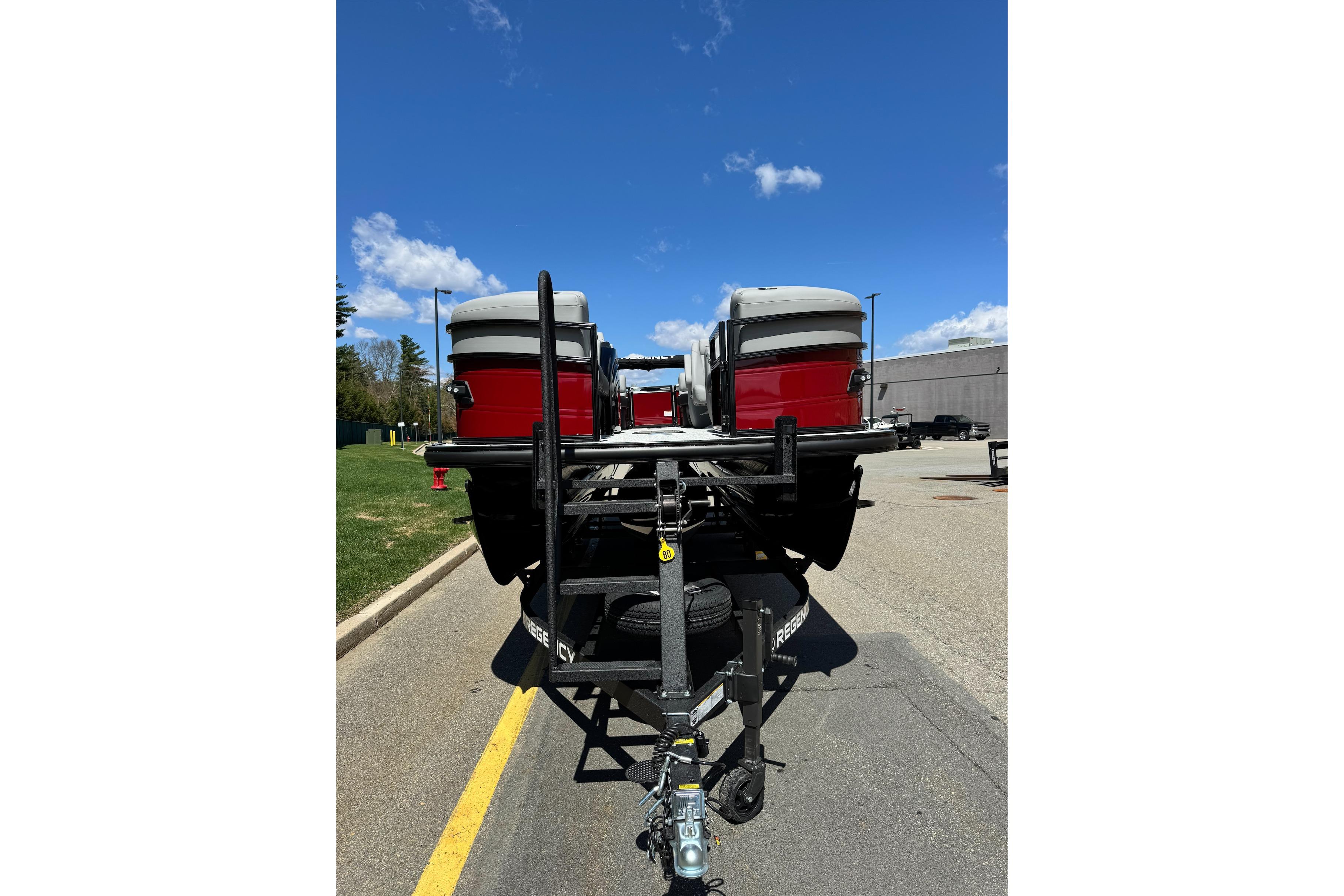 Rear view of a 2026 Regency 230 DL boat on a trailer under a clear blue sky.