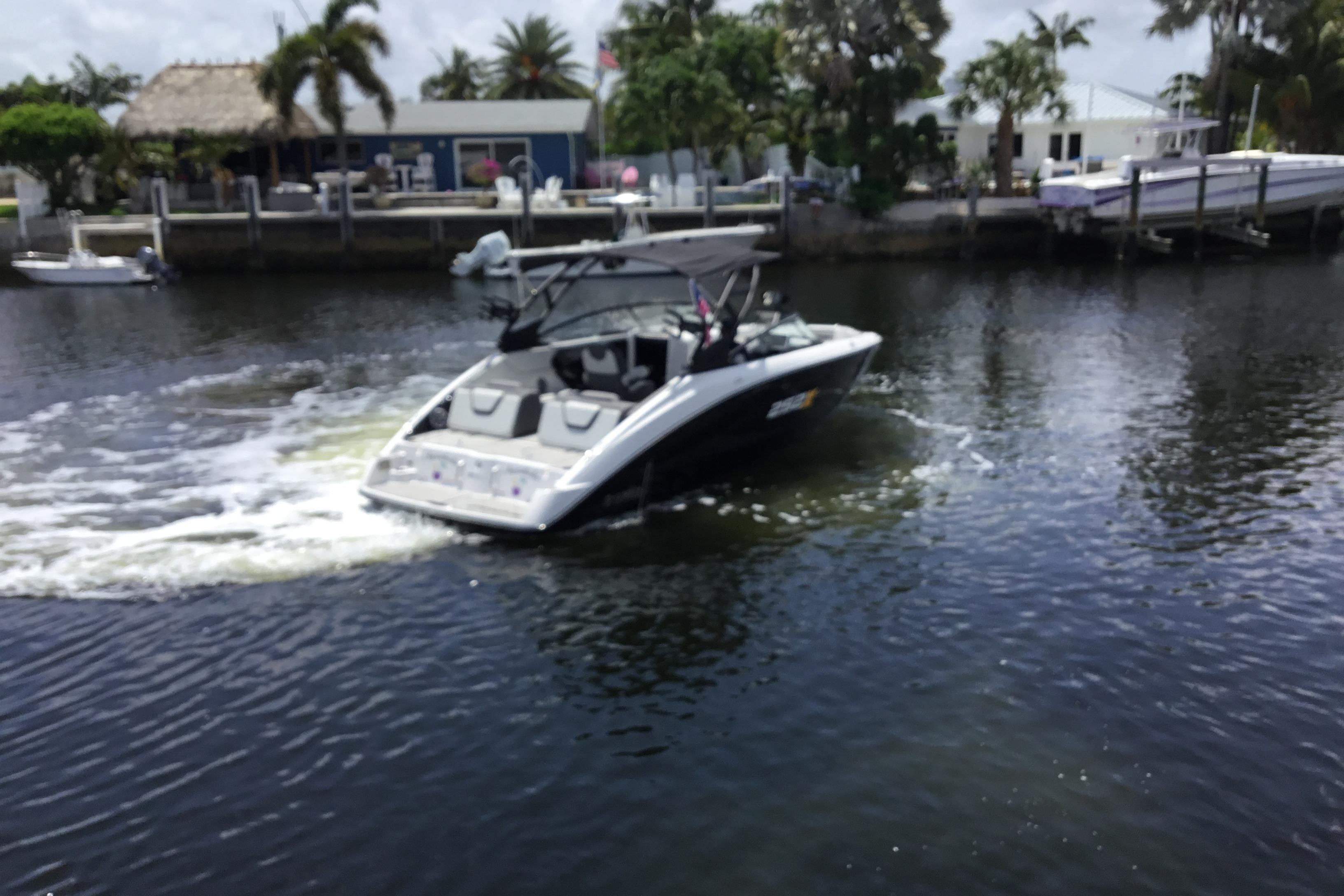 2023 Yamaha Boats 252XE cruising on a calm waterway near a tropical dock.