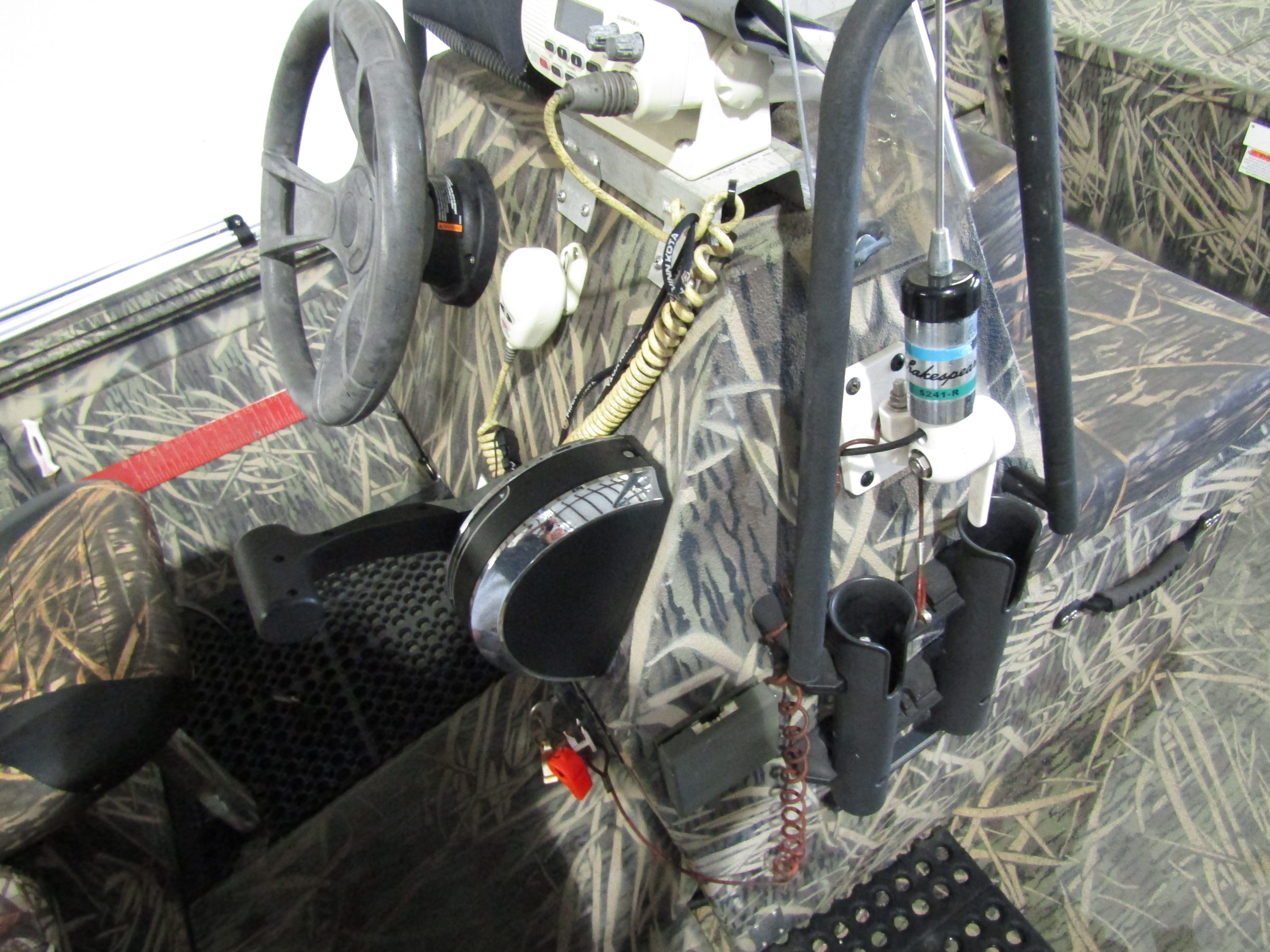 The image shows a boat cockpit with a camouflage pattern and various control devices.