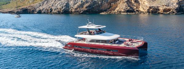 2025 Lagoon SIXTY 7 yacht cruising near rocky coastline.