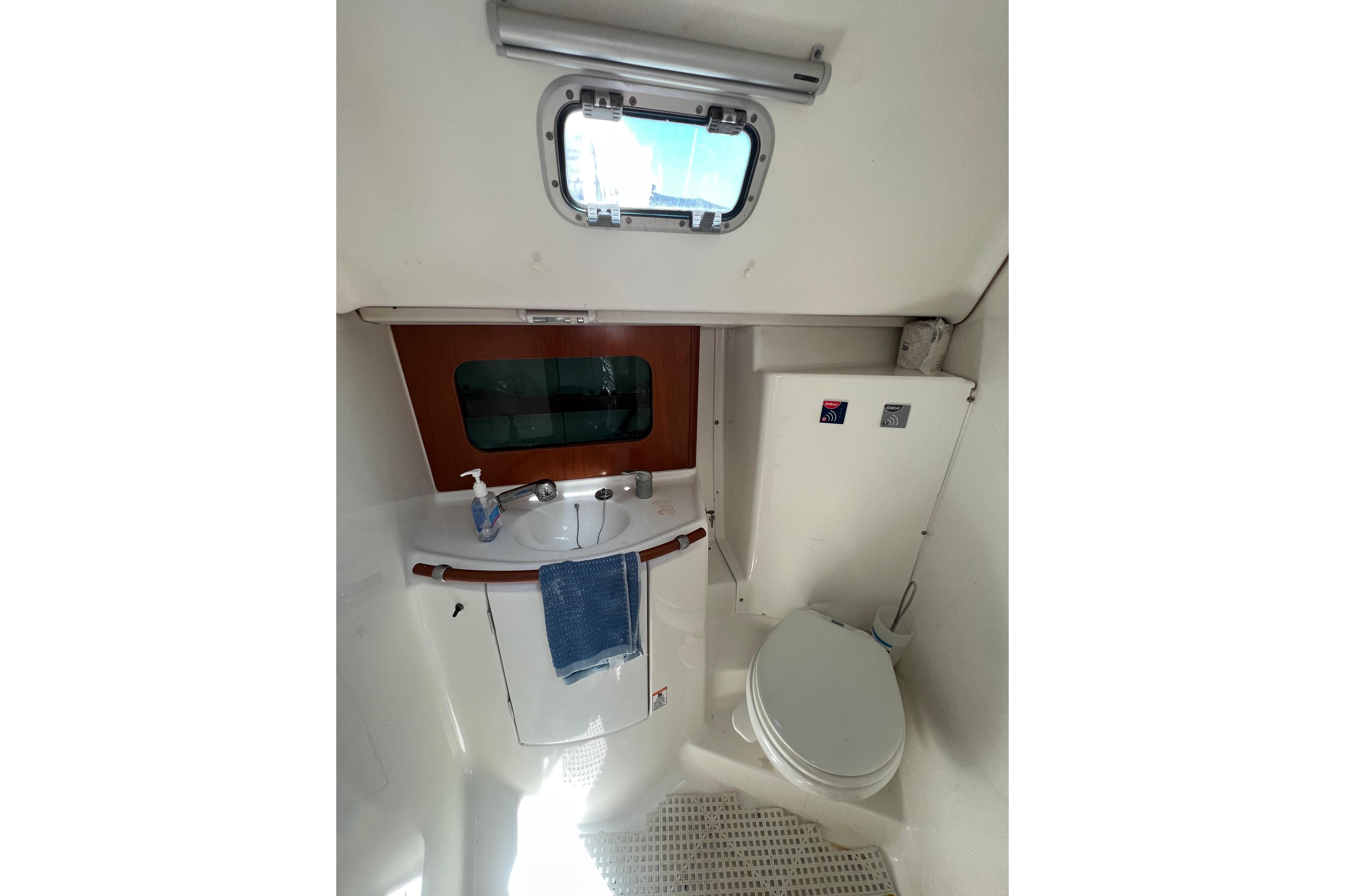 Bathroom interior of 2001 Beneteau 331 sailboat, featuring sink, toilet, and window.