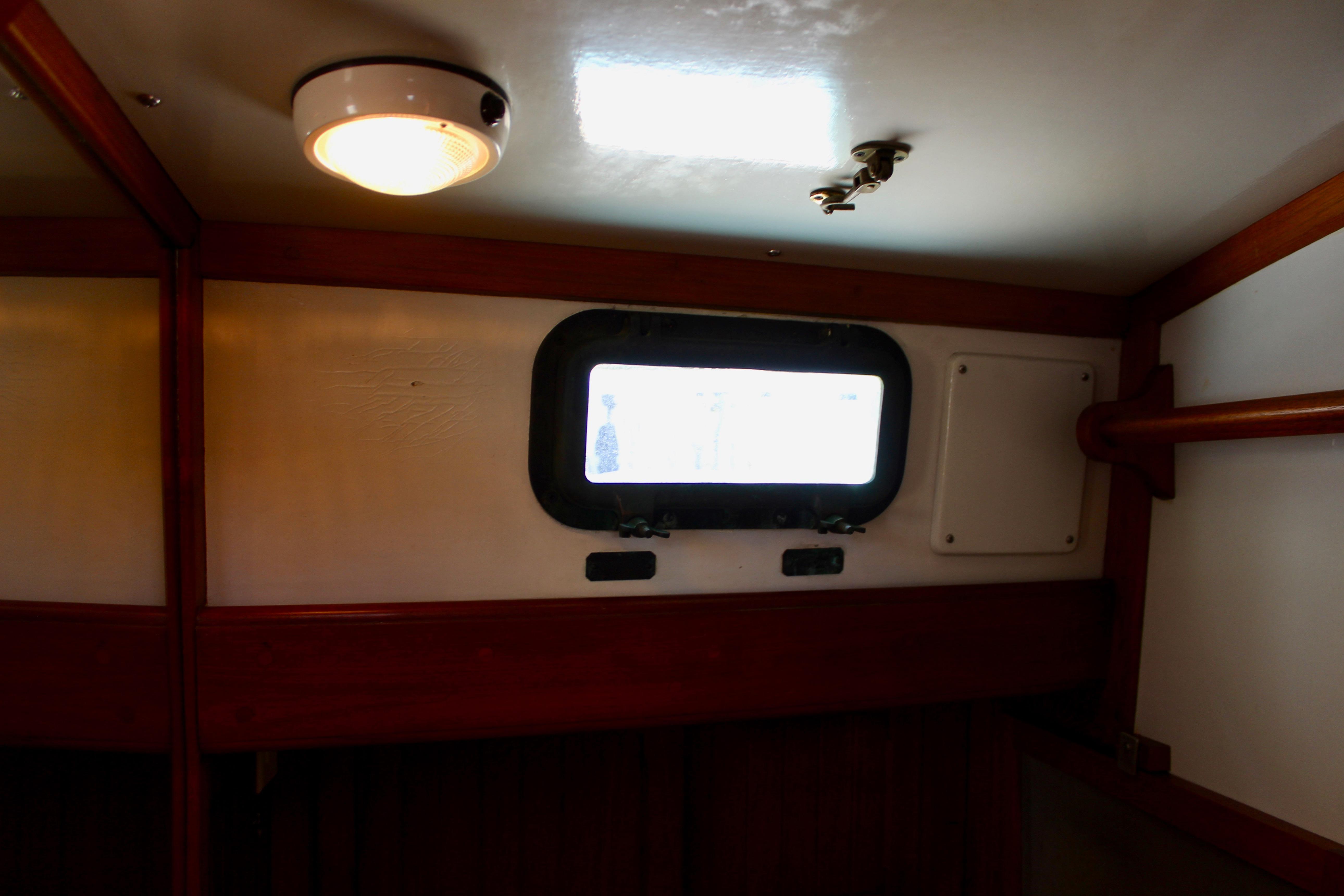 Interior of 1981 Kelly Peterson 46 sailboat with porthole and wooden trim.