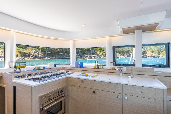 Modern kitchen interior of 2025 Lagoon 43 yacht with scenic ocean view.