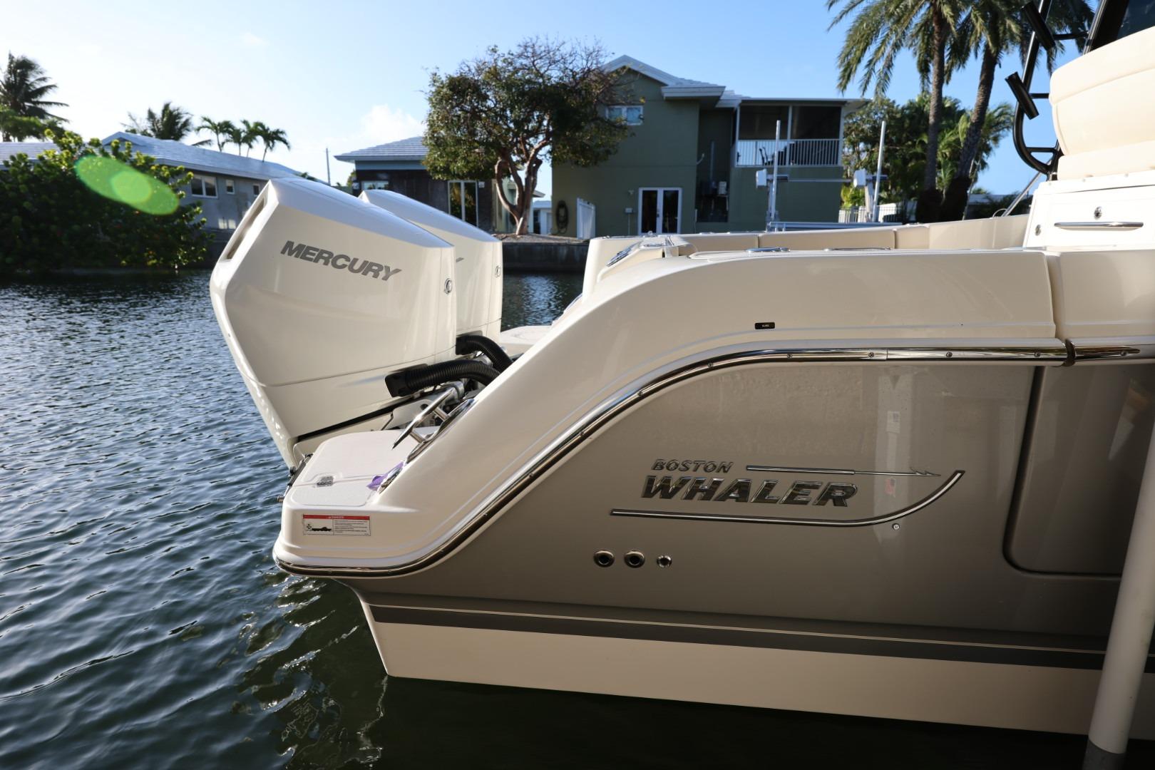 2025 Boston Whaler 325 Conquest with Mercury engine docked by waterfront homes.