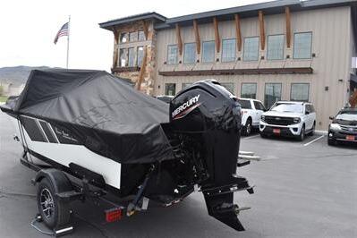 2026 Lowe Fishing Machine 1675 WT boat with Mercury engine, parked outside a modern building.