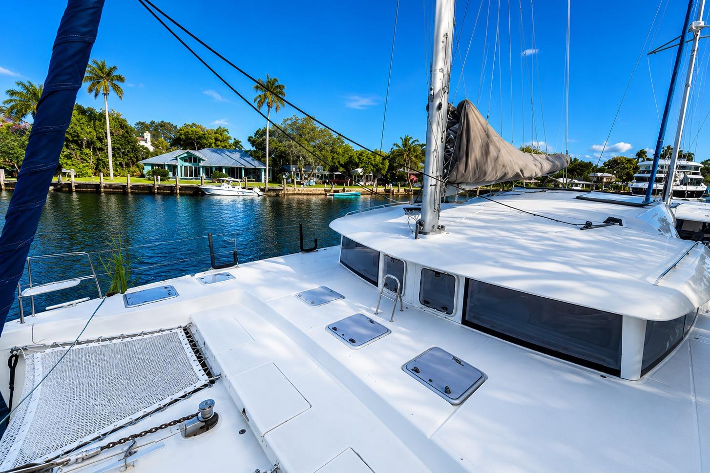 2010 Lagoon 421 catamaran docked by a scenic waterfront with palm trees.