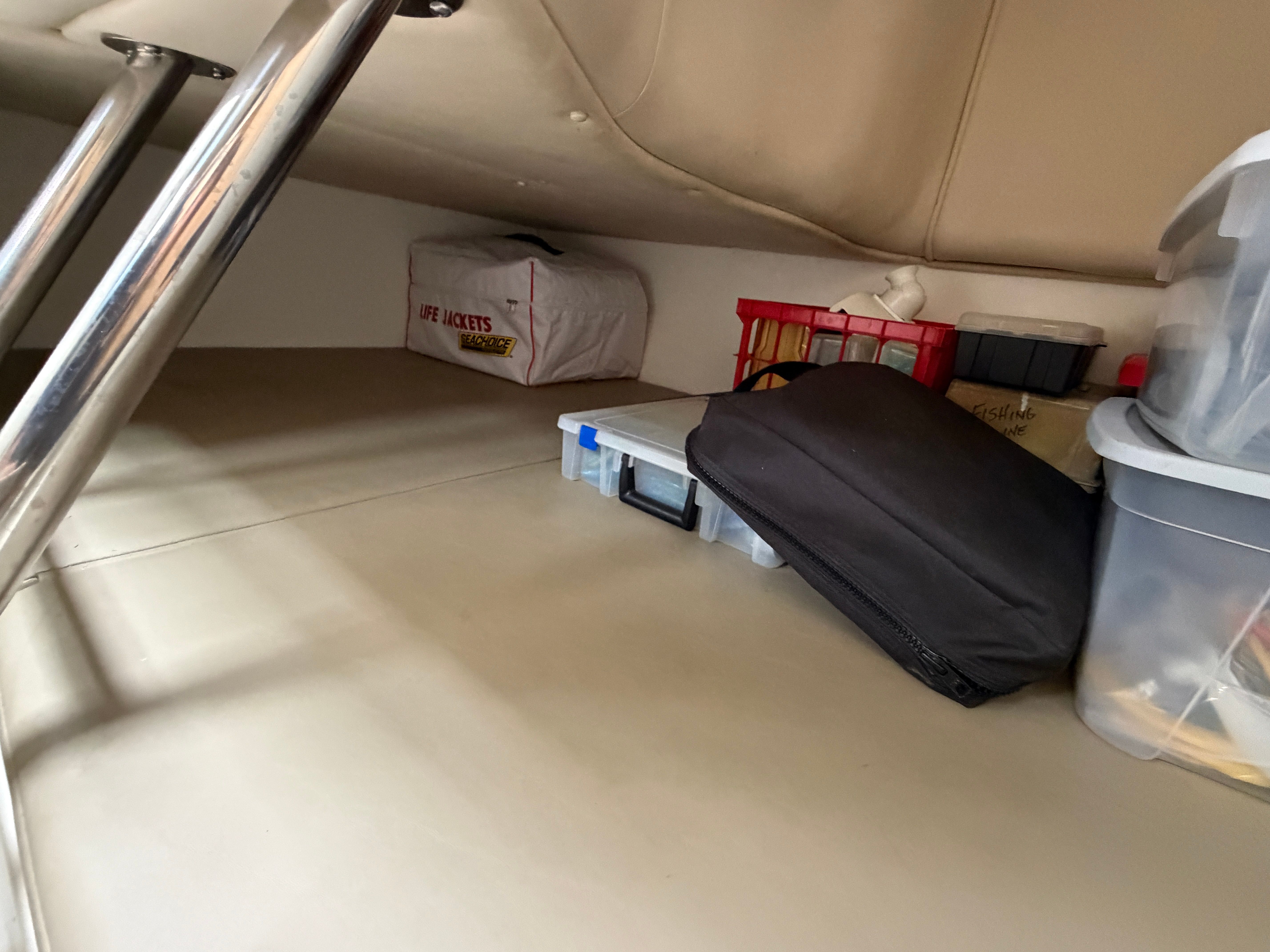 Under-deck storage area with various boxes and a bag.