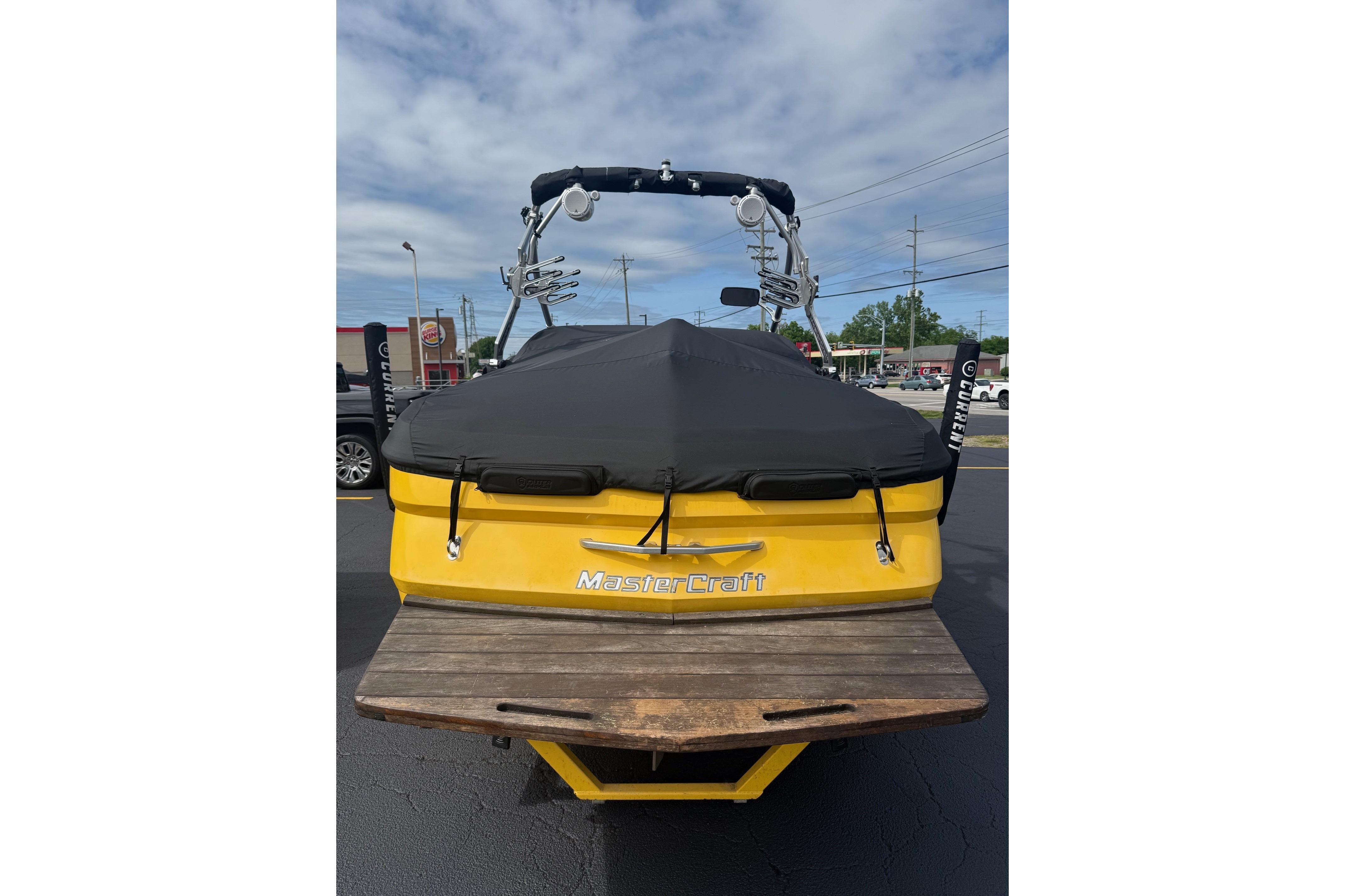 2008 MasterCraft X-15 boat, yellow with black cover, parked outdoors.
