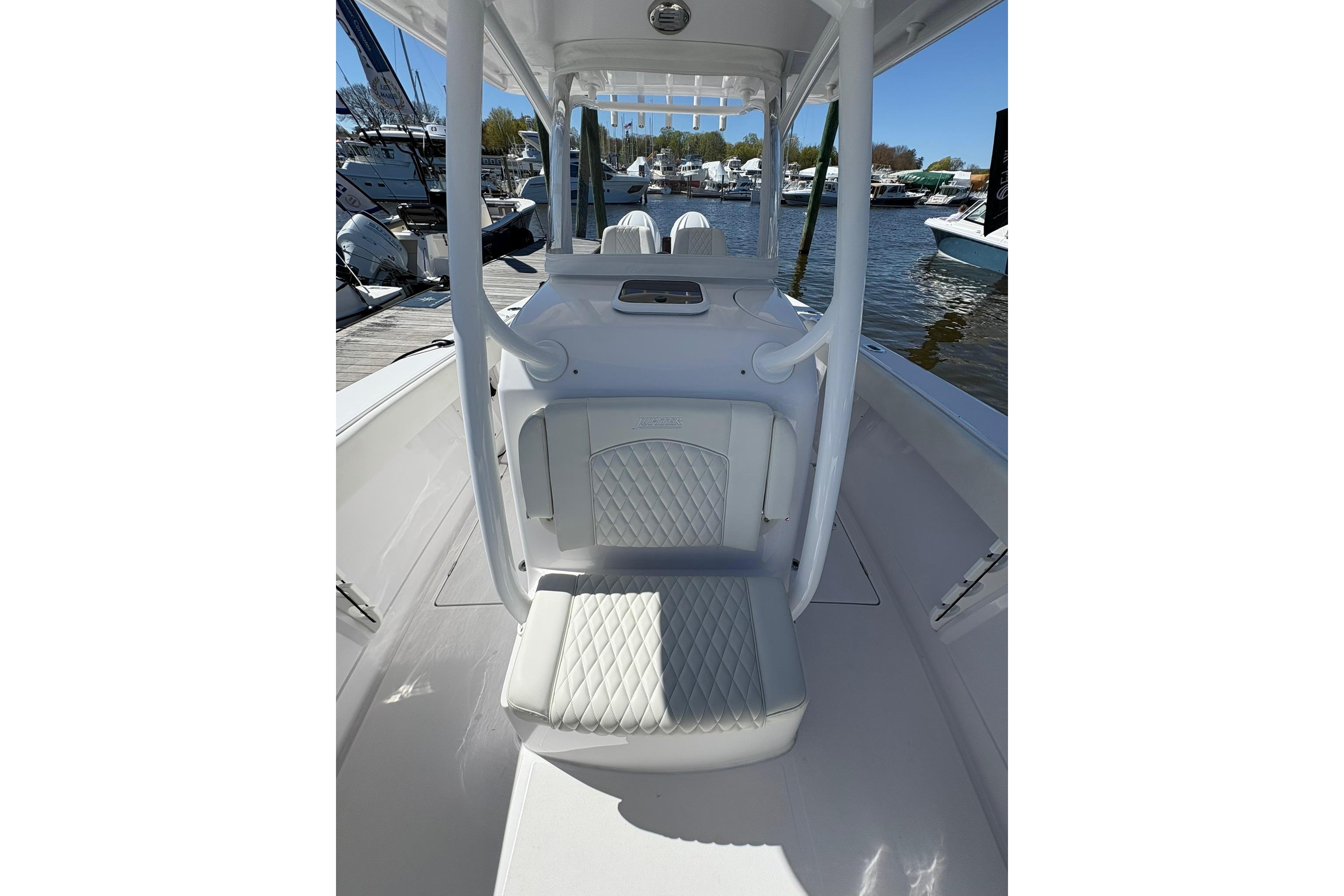 2023 Jupiter 30 boat interior with white cushioned seating at a marina.