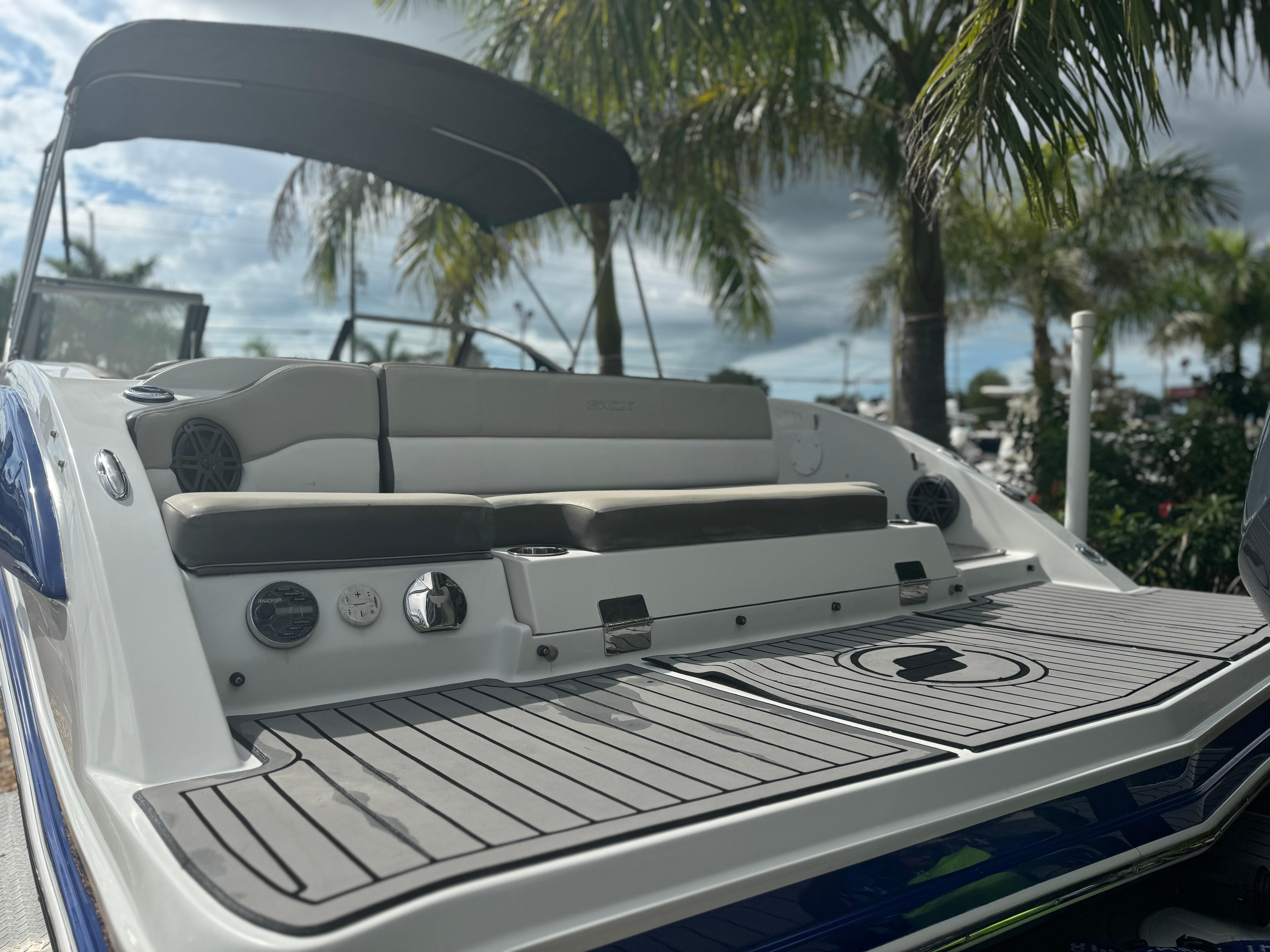 2017 Starcraft 230 OB SCX EXT boat with seating, under a canopy, surrounded by palm trees.