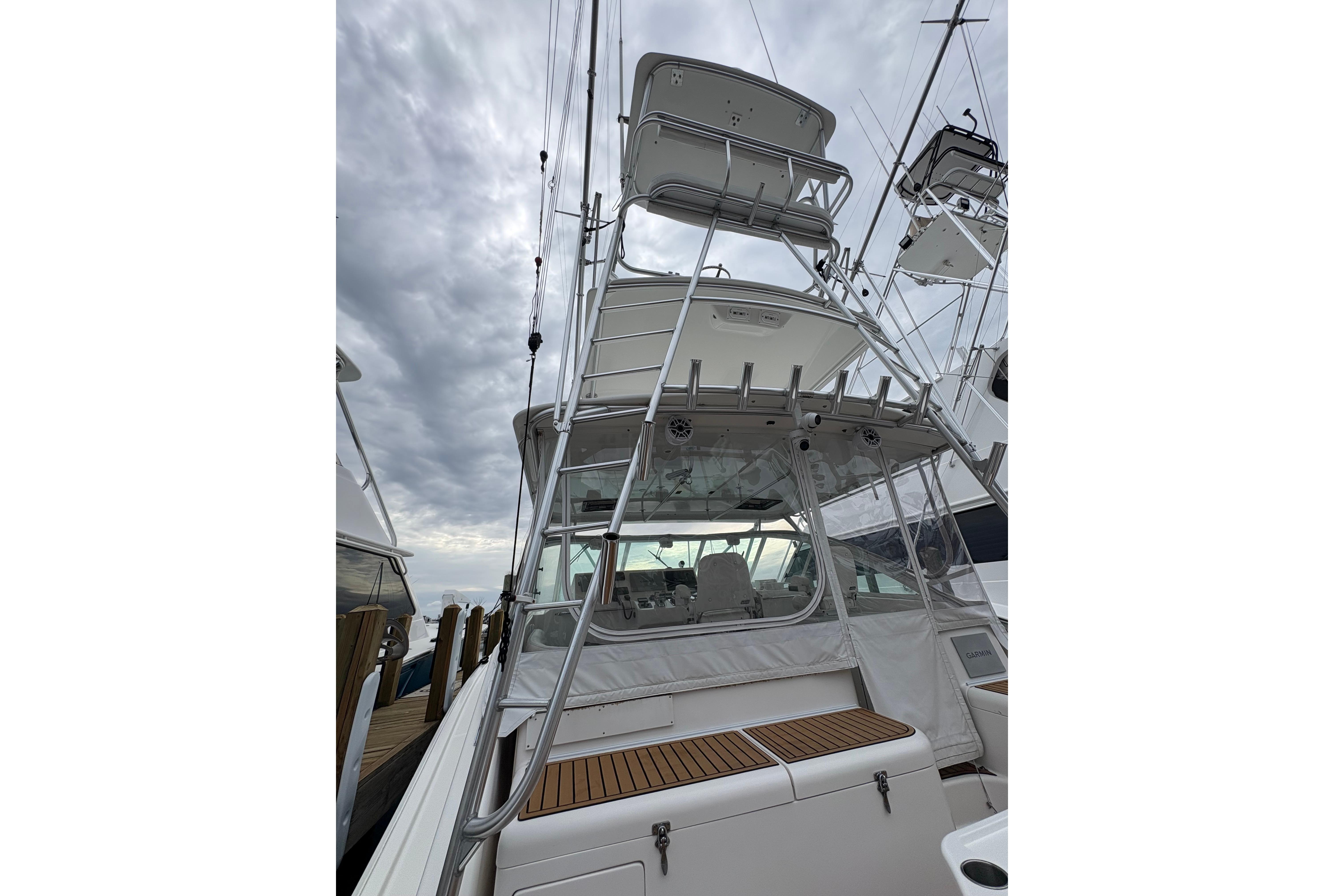 2004 Cabo 40 Hardtop Express boat with tower, docked under cloudy skies.