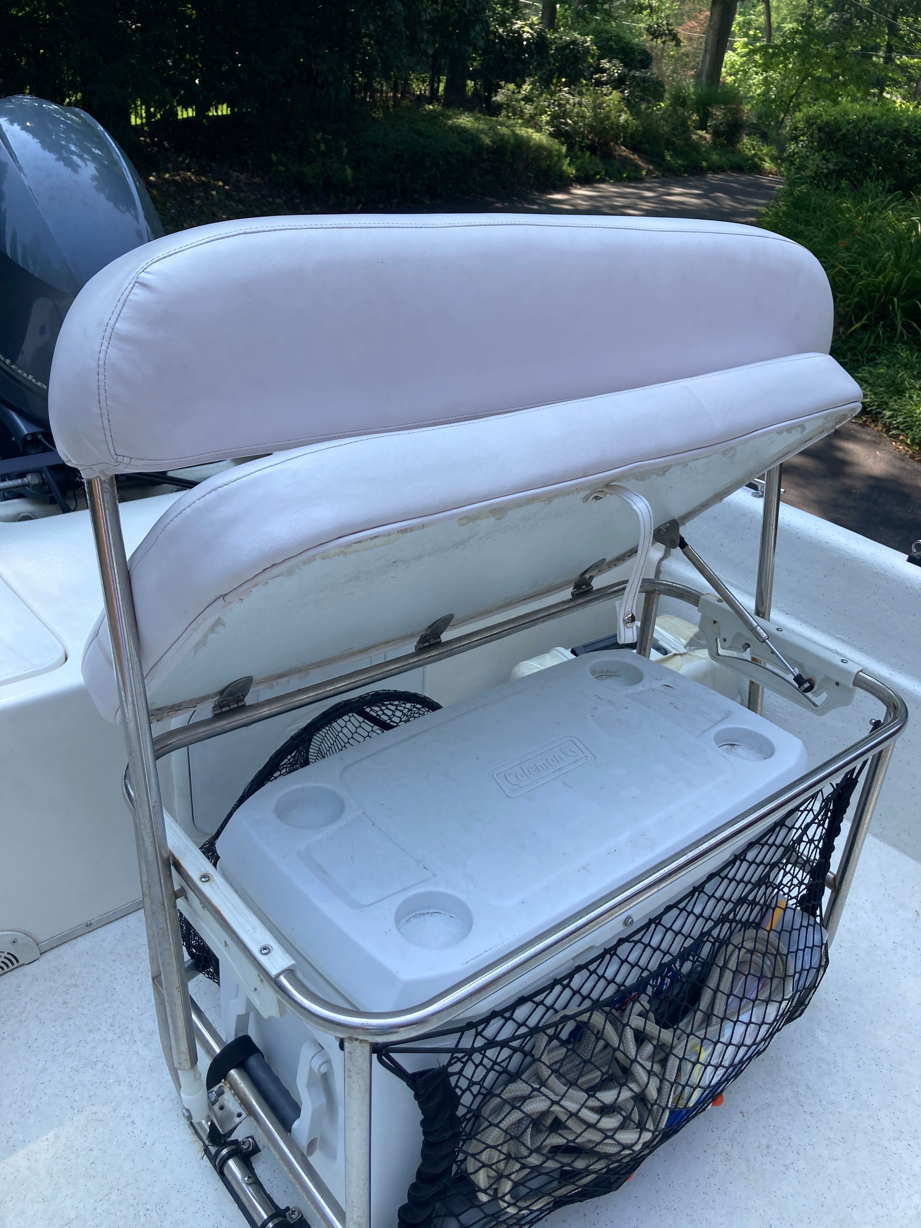 The image shows a white bench seat on a boat with a cooler stored underneath.