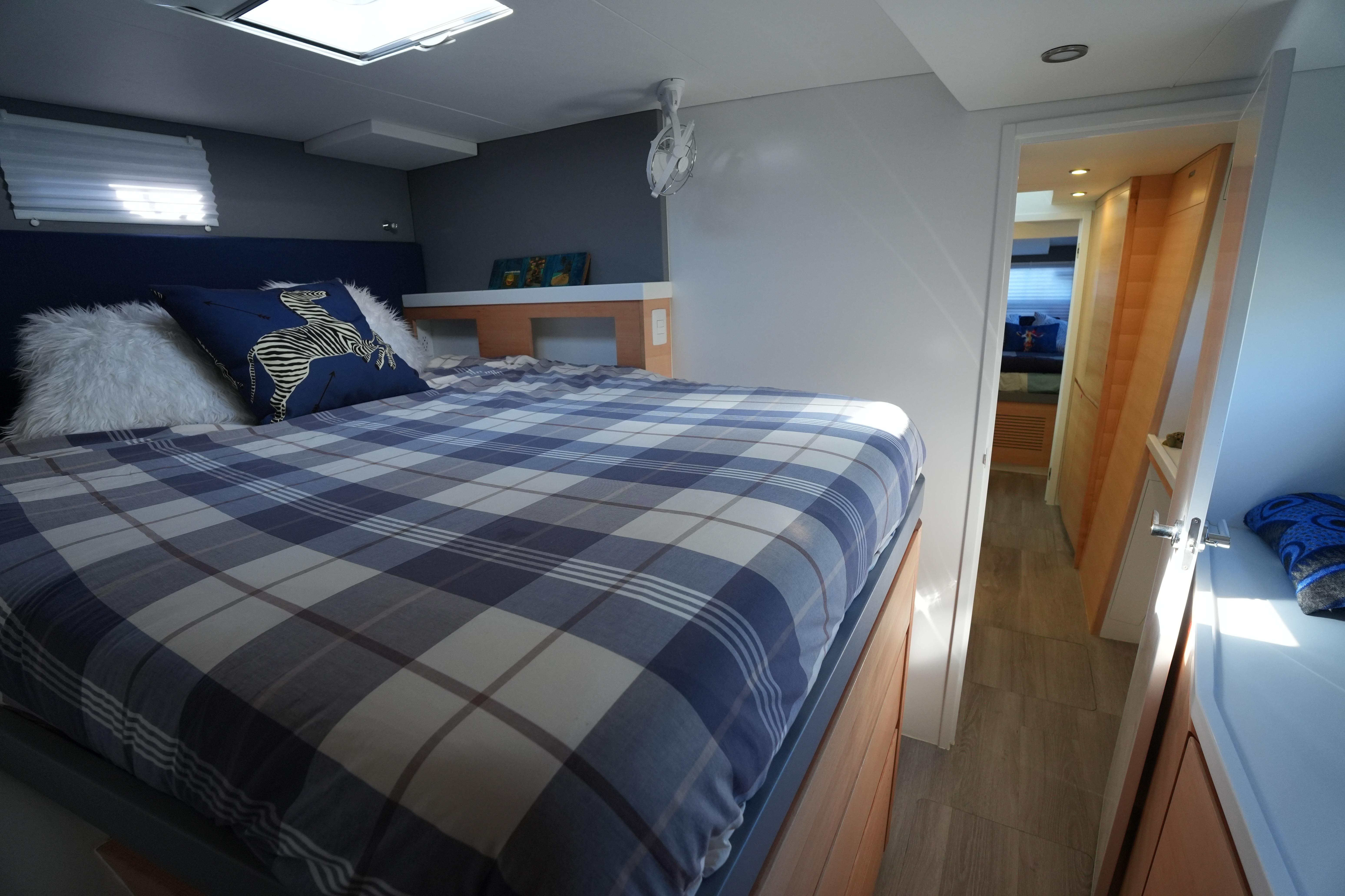 Cozy bedroom in 2024 Balance 442 yacht with plaid bedding and modern decor.