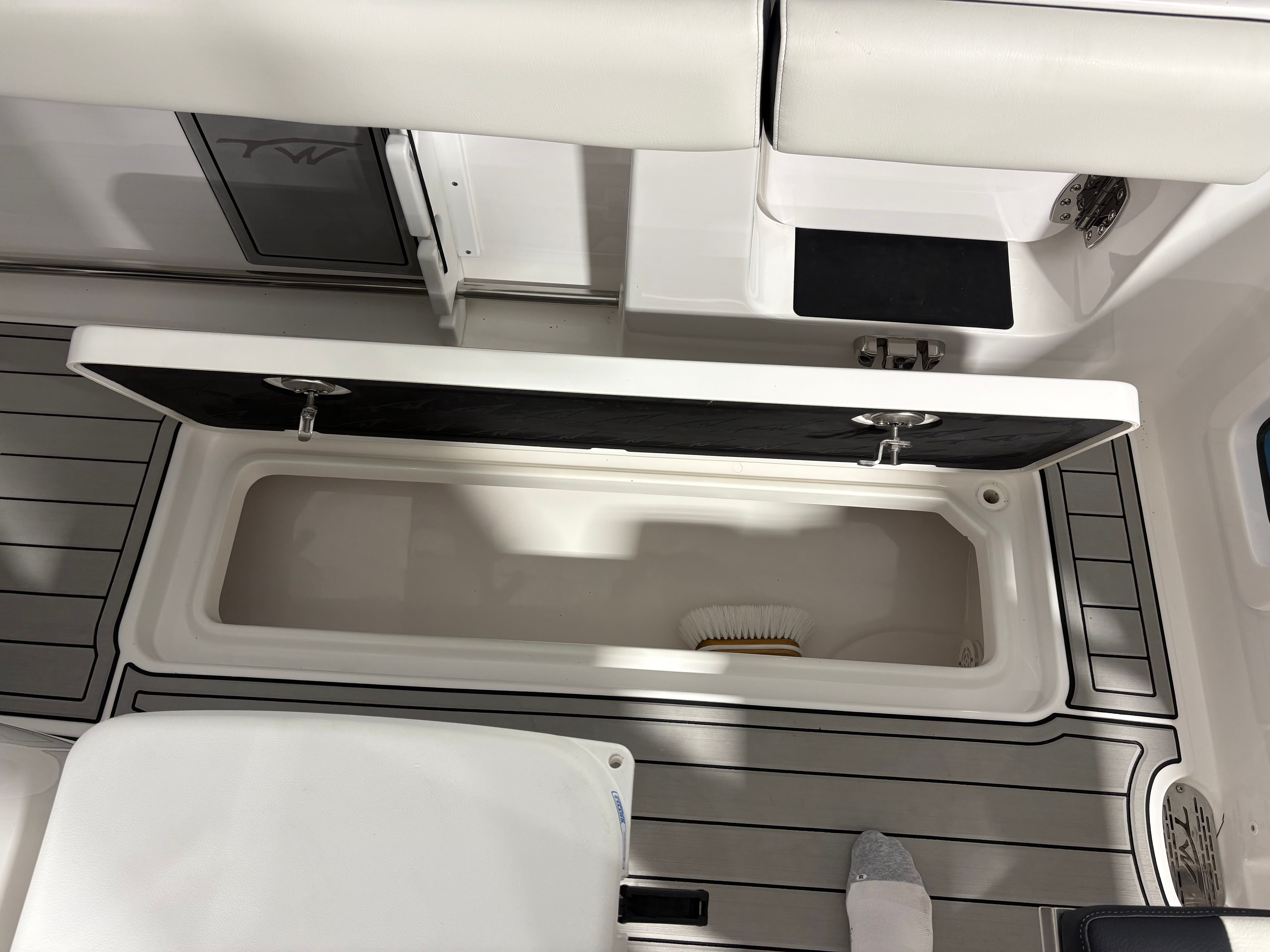 The image shows the deck of a Tidewater 302 CC Adventure boat with an open storage compartment.