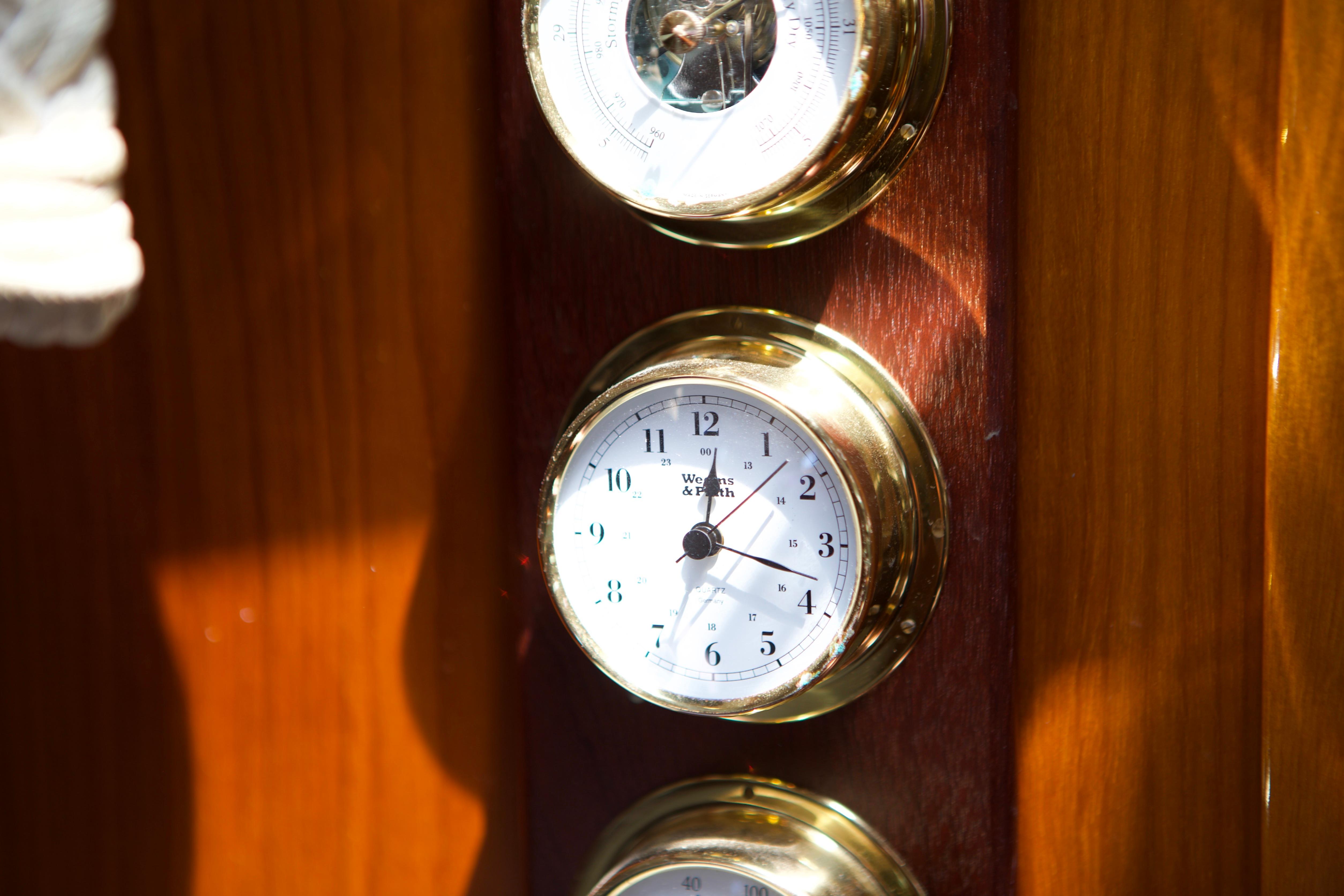 Brass clock and barometer on 2005 Beneteau 423 yacht's wooden interior panel.