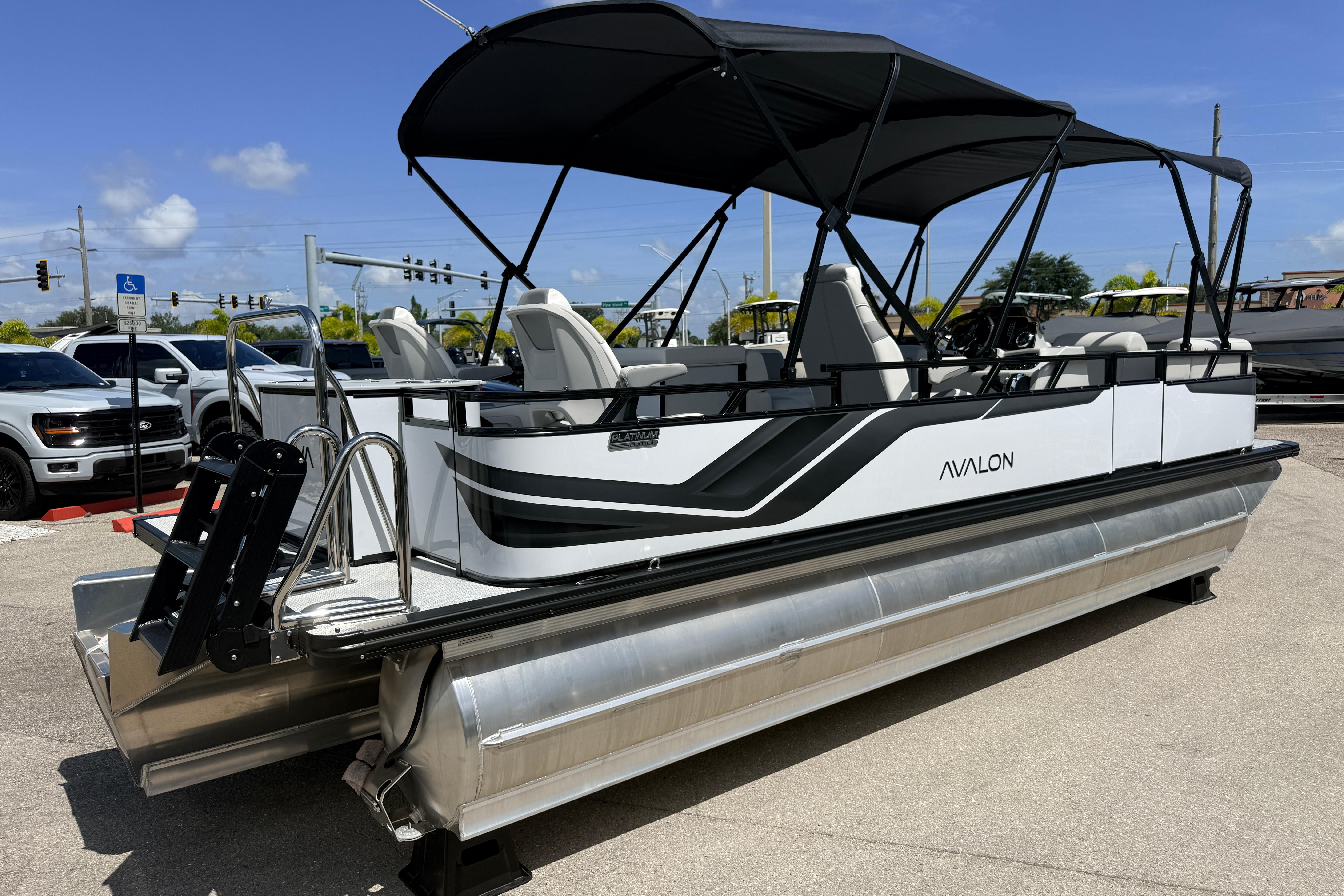 2026 Avalon 2385 Venture 85 Tri Toon boat with canopy, parked outdoors.