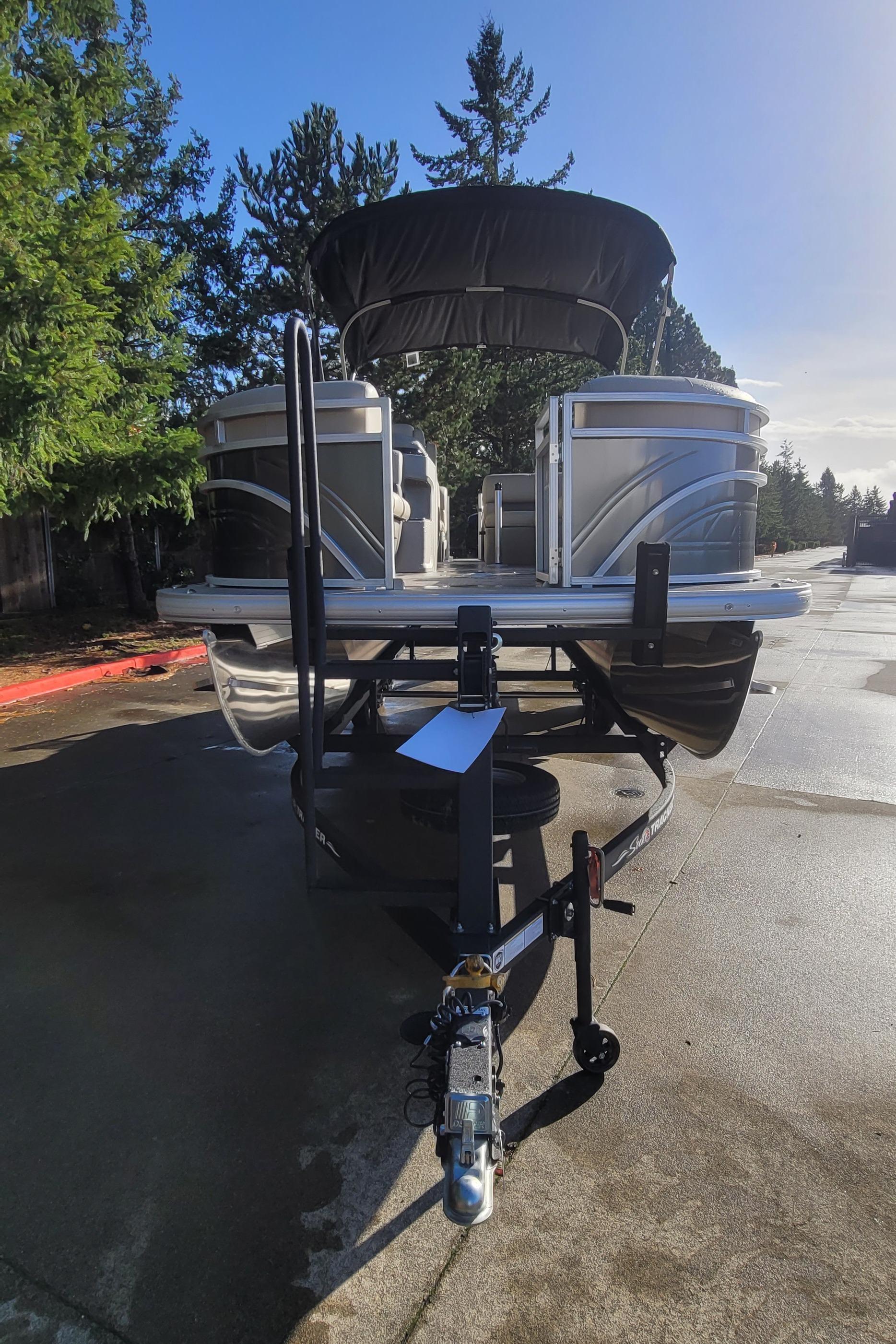2025 Sun Tracker Party Barge 22 RF DLX pontoon boat on trailer, parked outdoors.