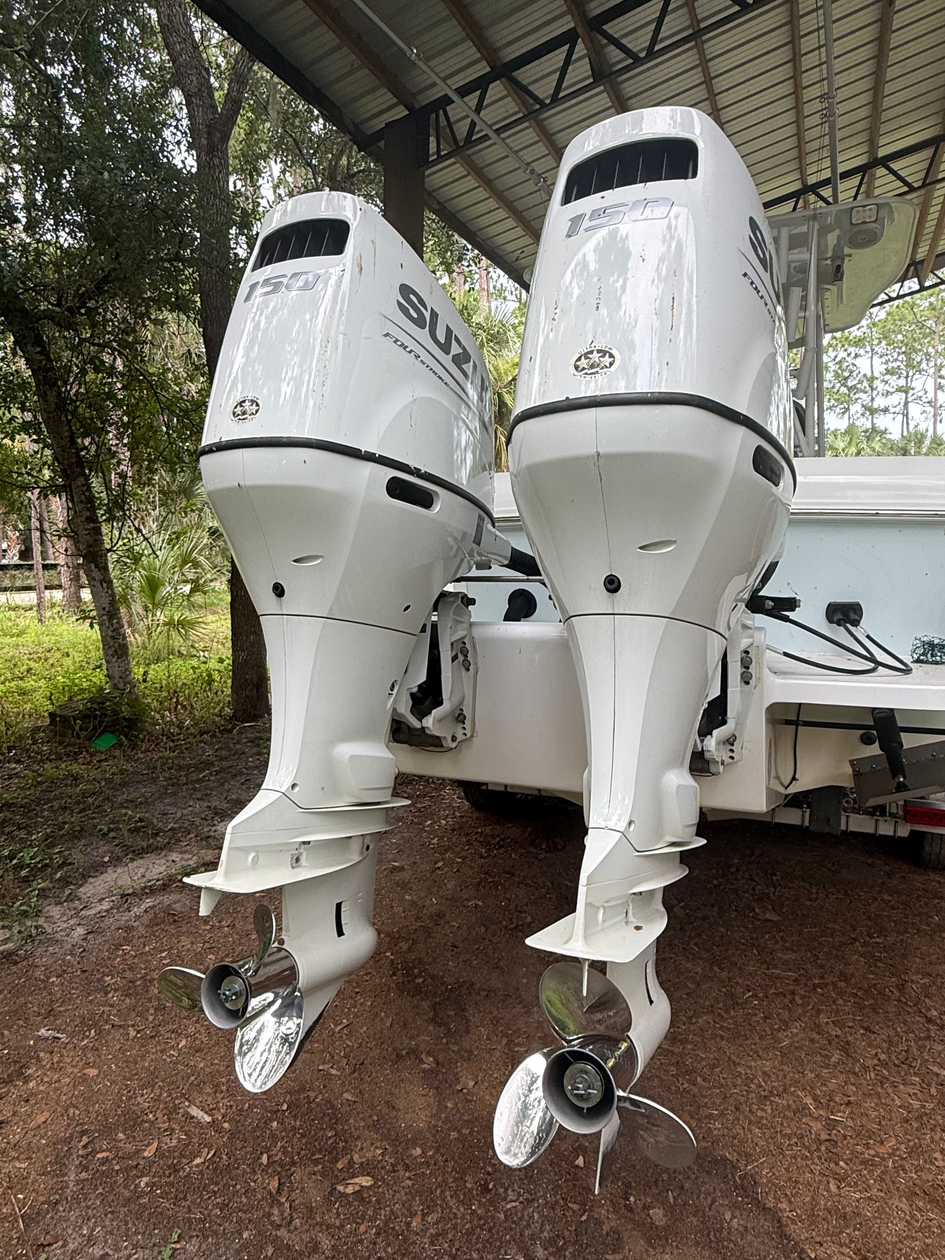 Two Suzuki outboard motors are mounted on the stern of a boat, which is on a trailer.