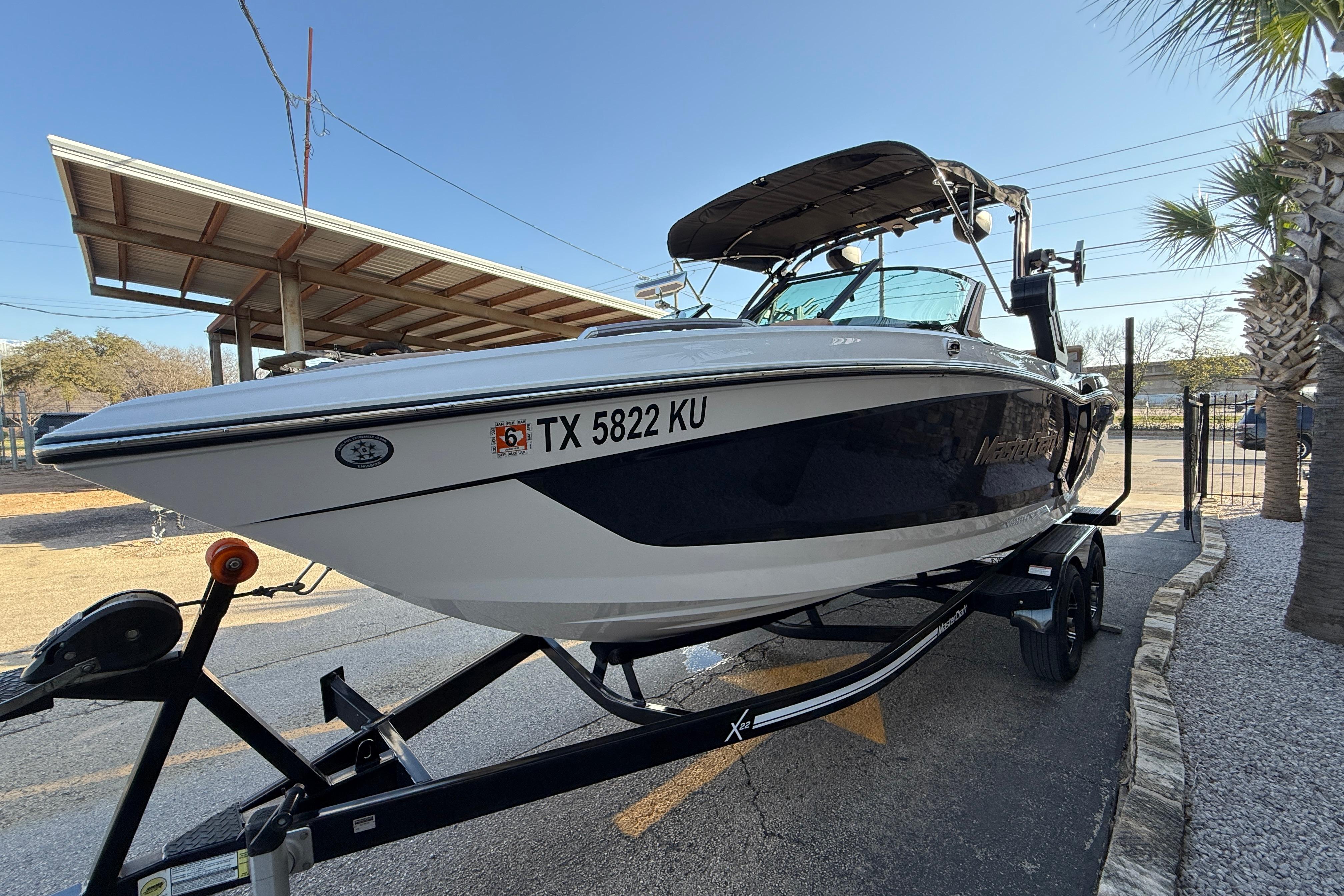 2023 MasterCraft X22 boat on trailer, parked outdoors under clear sky.