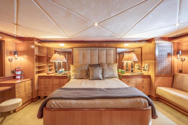 Luxurious master bedroom on a 2001 Grand Harbour 76 yacht with elegant wooden furnishings.