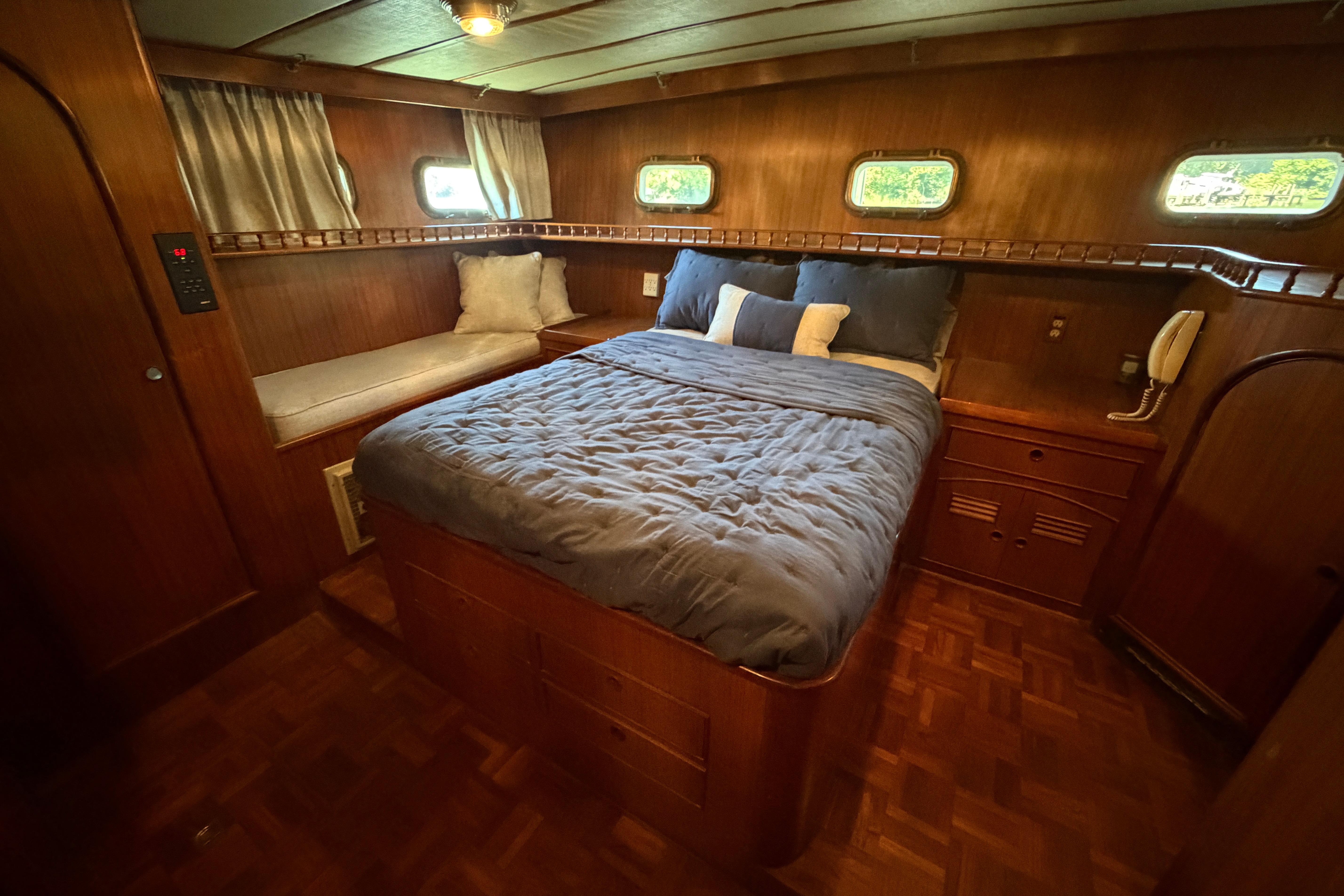 Luxurious 1981 Marine Trader 50 yacht bedroom with wood paneling and cozy bedding.