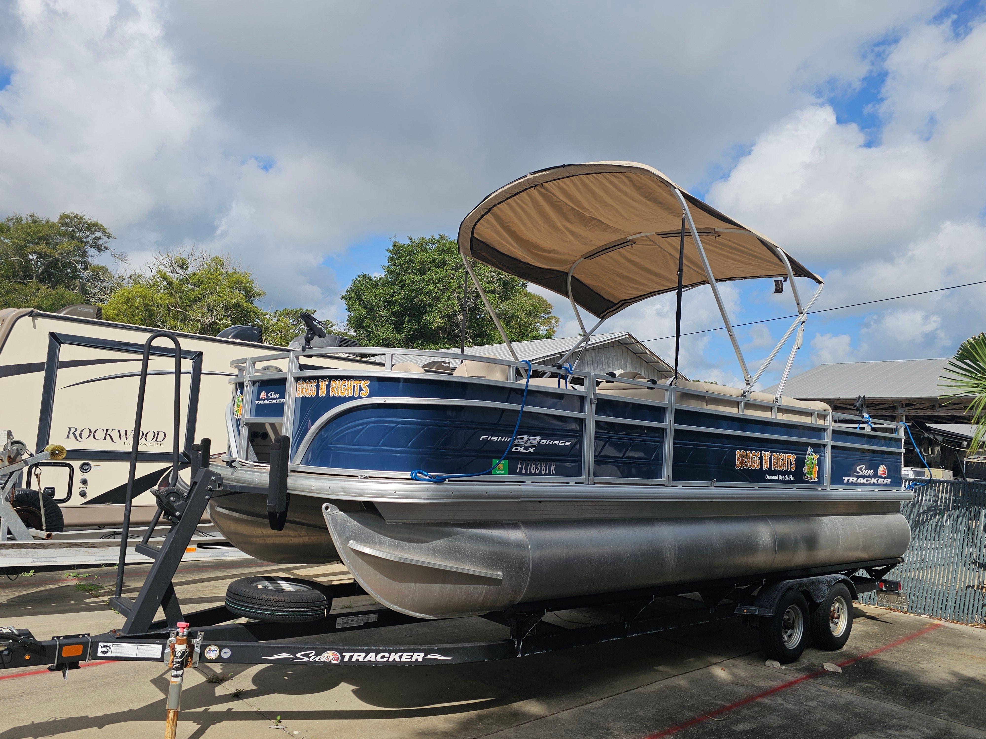 2024 Sun Tracker Fishin' Barge 22 DLX on trailer, blue sky.