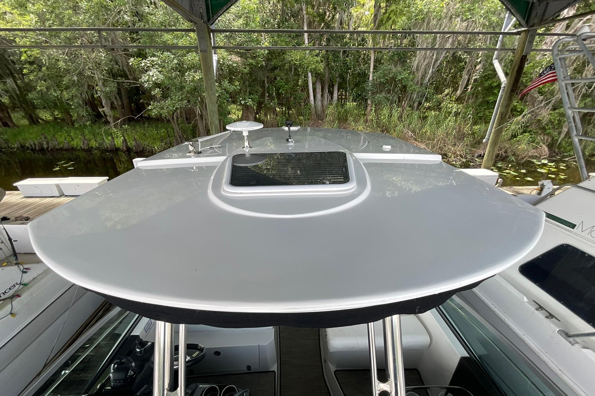 2019 Monterey 335 Sport Yacht bow view with lush greenery backdrop.
