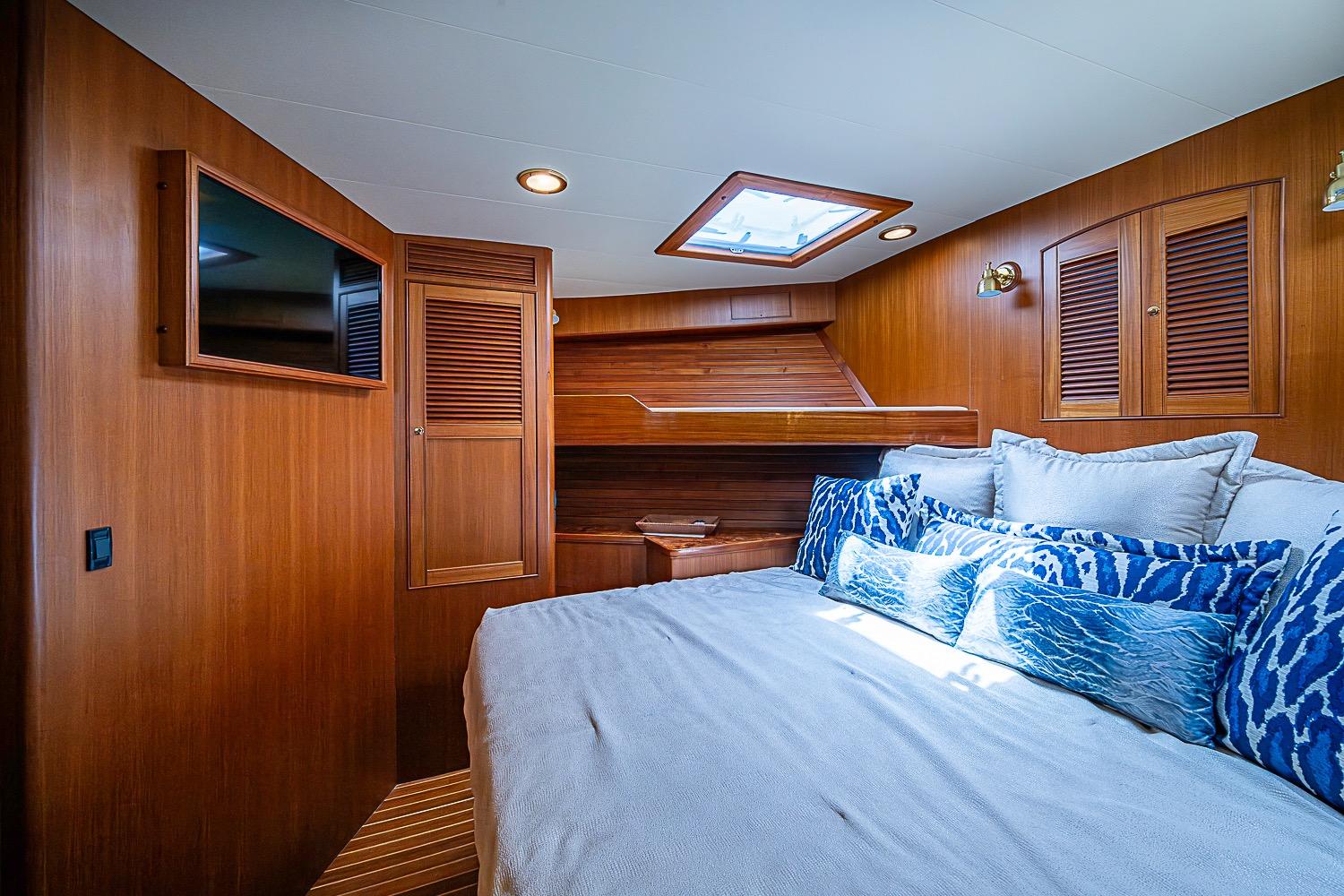 Luxurious cabin interior of 2014 Marlow 80 Explorer yacht with wood paneling and plush bedding.