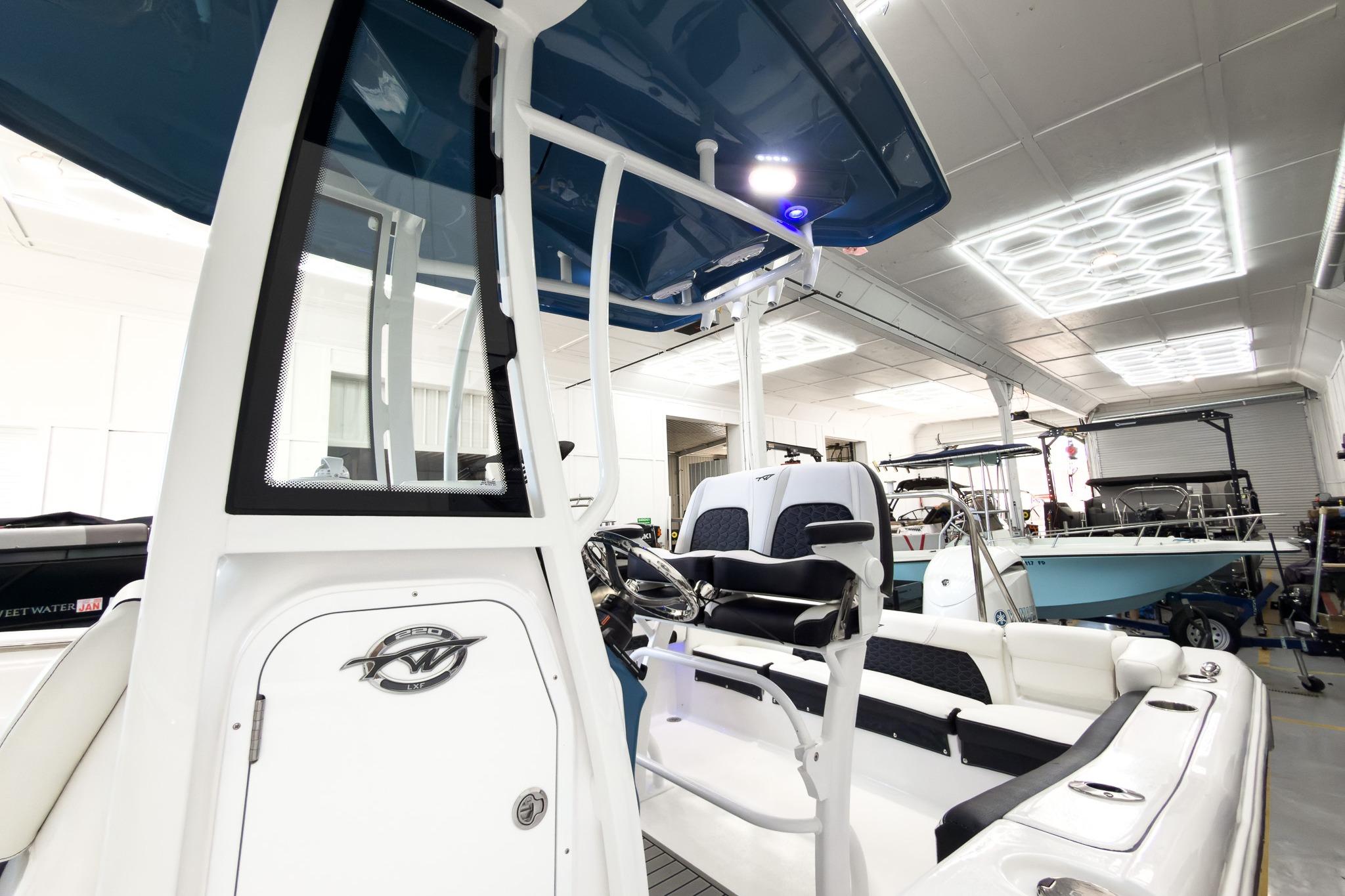 The image shows a modern boat with blue accents and sleek seating in a showroom.