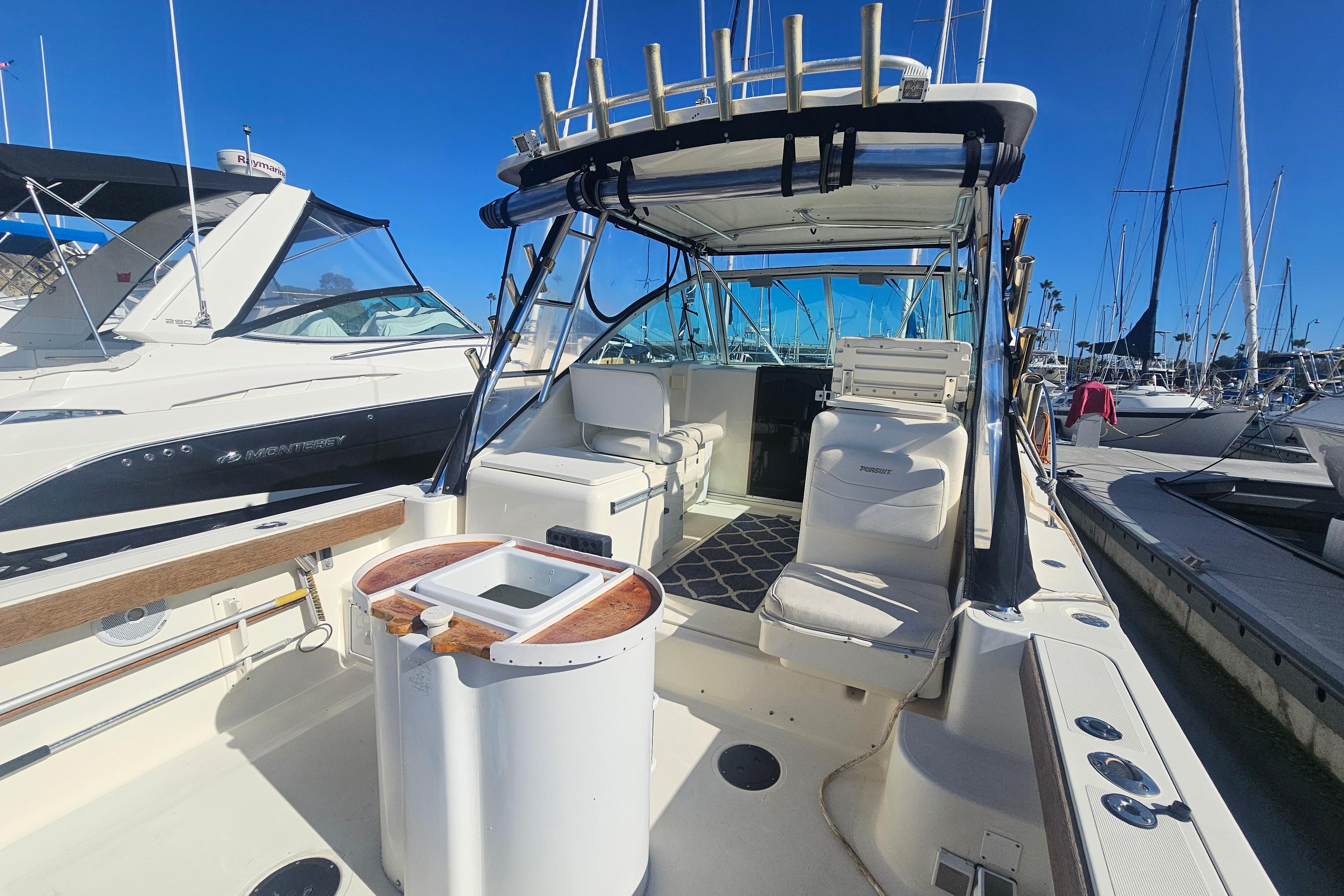 2001 Pursuit 3000 Express boat docked, featuring spacious seating and fishing rod holders.
