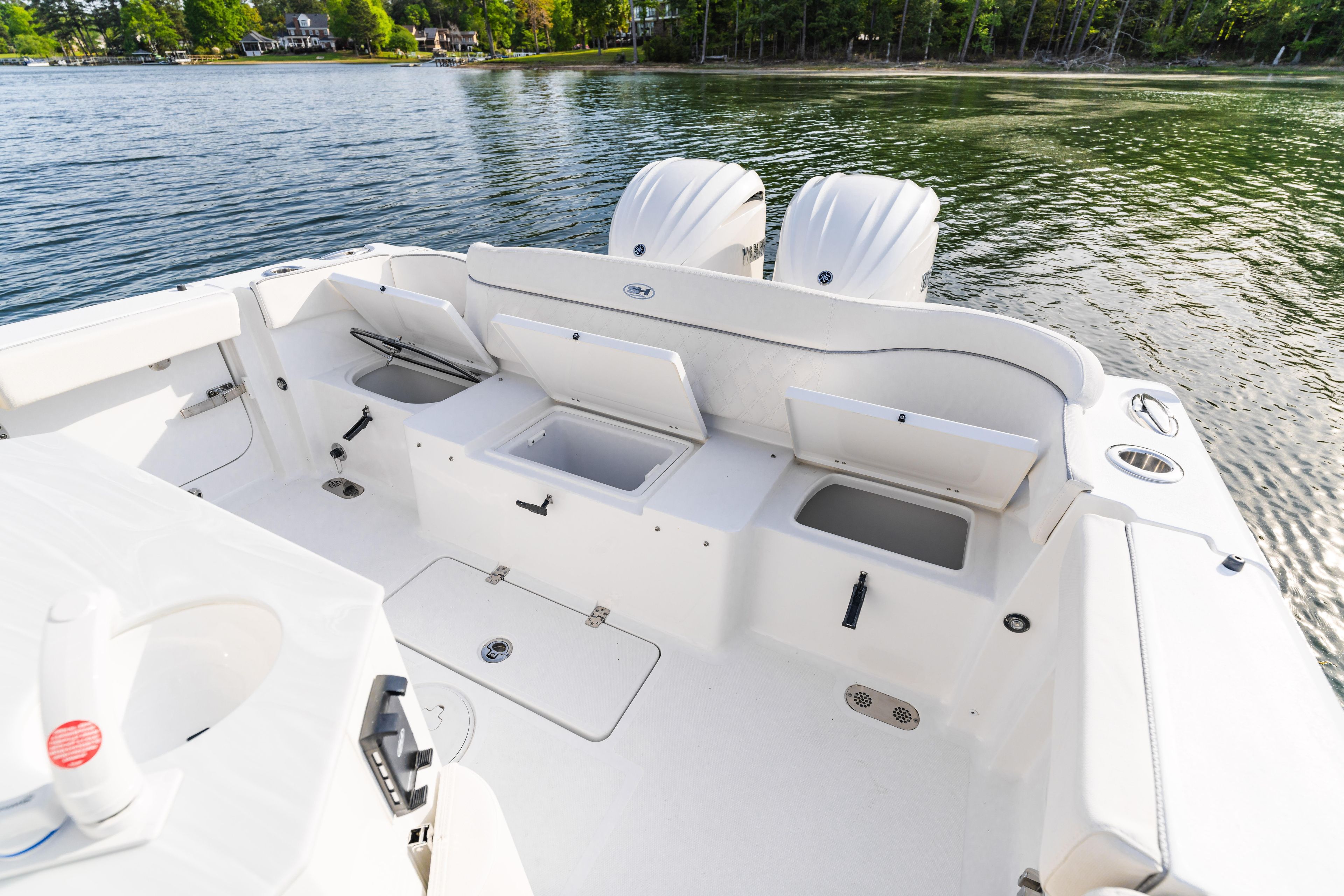 2027 Sea Hunt Ultra 275 SE boat with open storage compartments on a serene lake.
