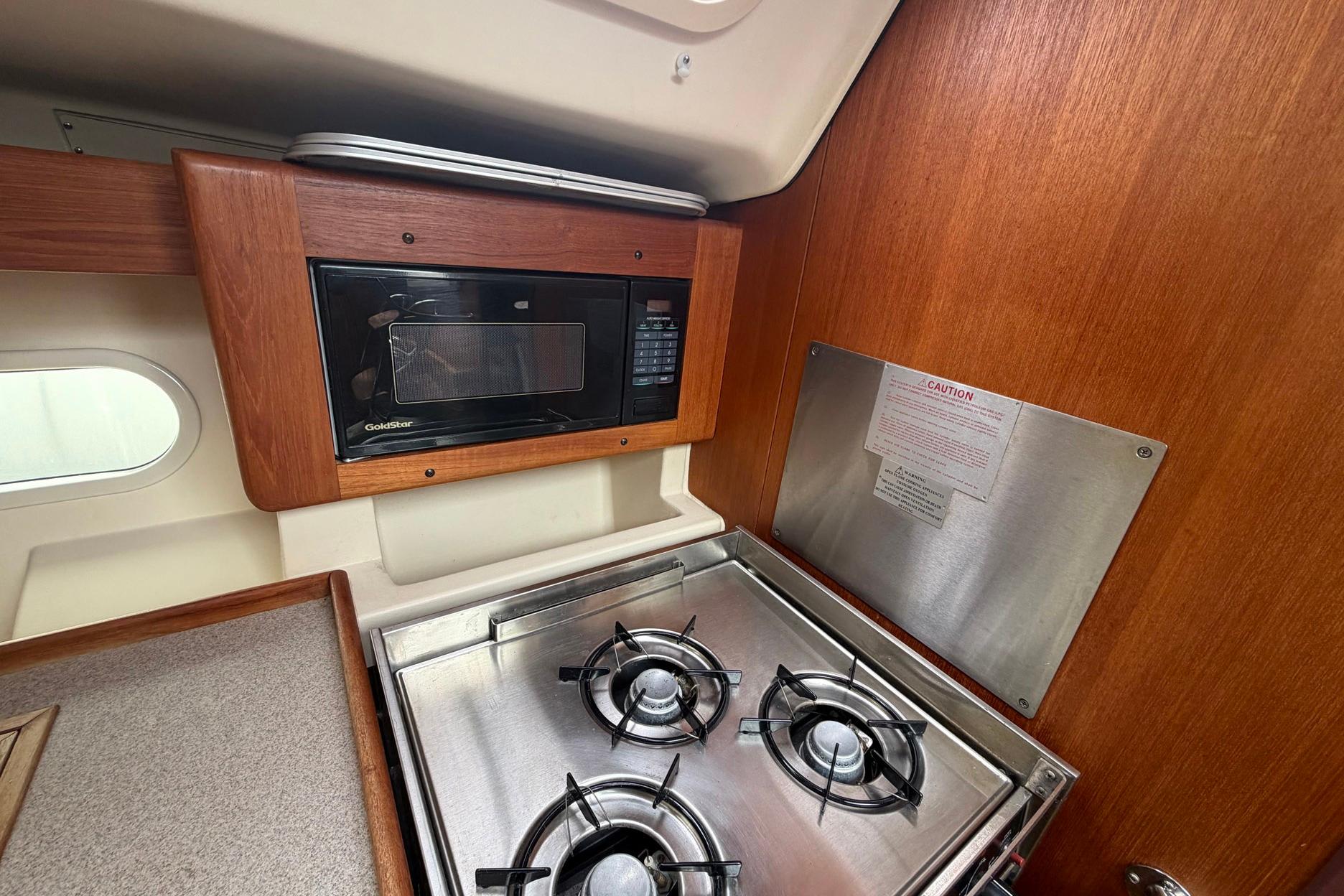 Compact kitchen area in a 1998 Hunter 410 sailboat with stove and microwave.