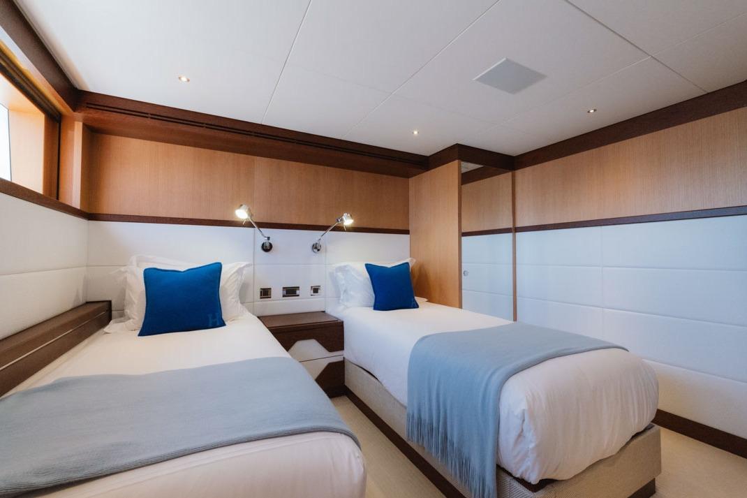 Luxurious twin cabin on 2016 Feadship Lagoon Cruiser yacht, featuring elegant decor and cozy bedding.