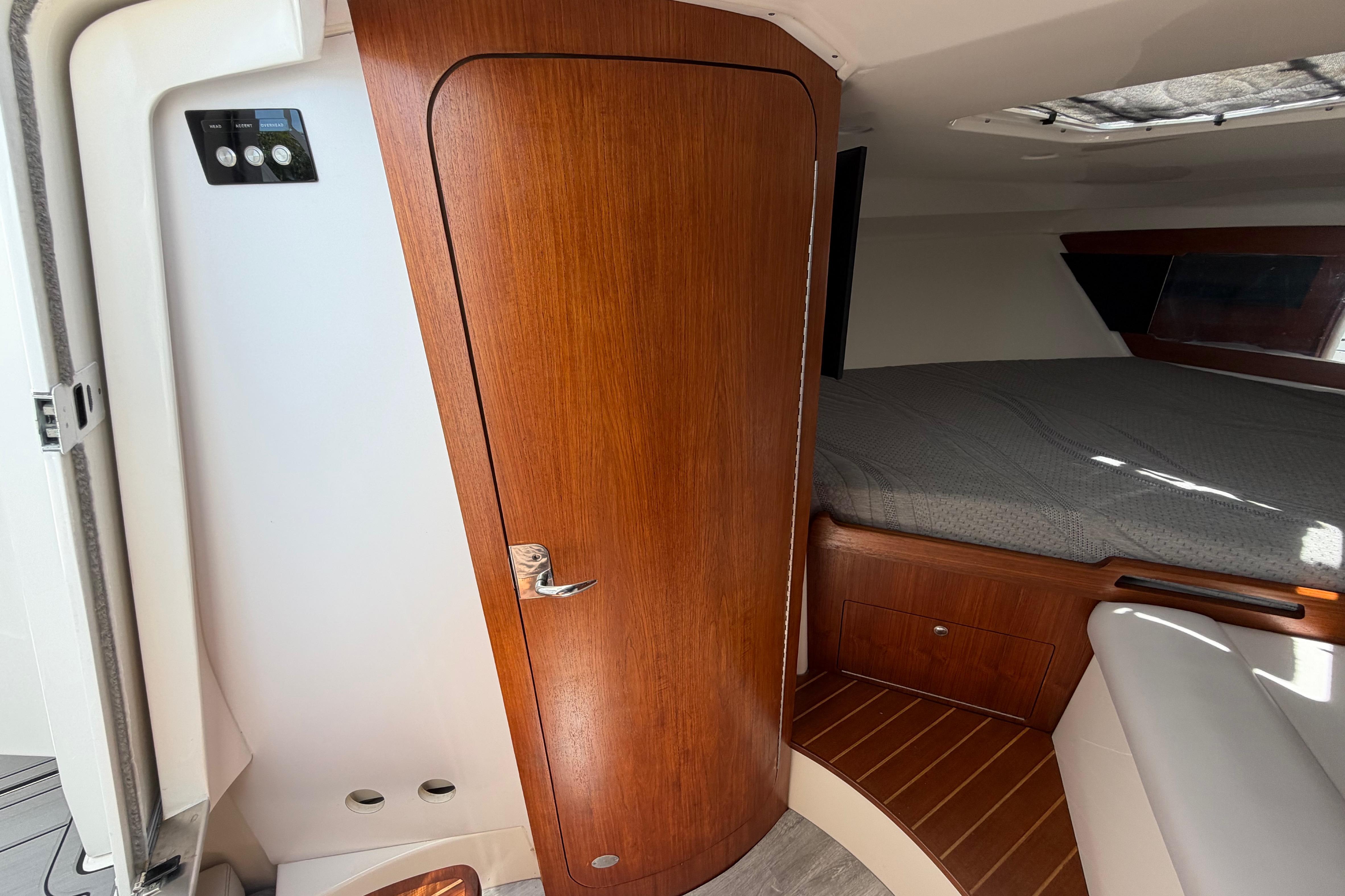 Interior cabin of 2009 Everglades 350LX boat with wooden door and cozy bed.