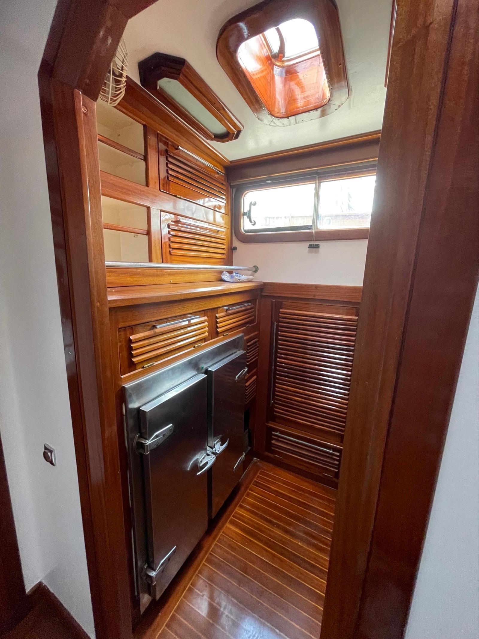 Interior of 1999 Custom Classic Schooner with wooden cabinetry and stainless steel appliances.