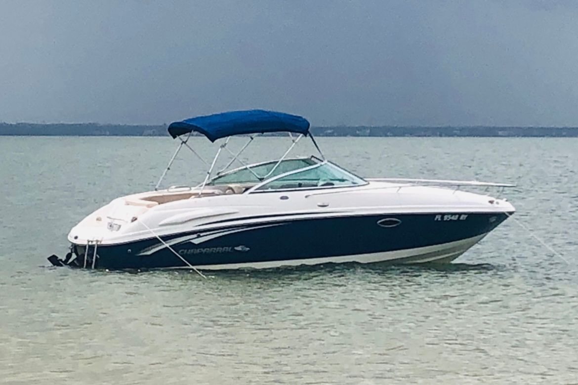 A 2007 Chaparral 235 SSi boat floats on calm water with a blue canopy.