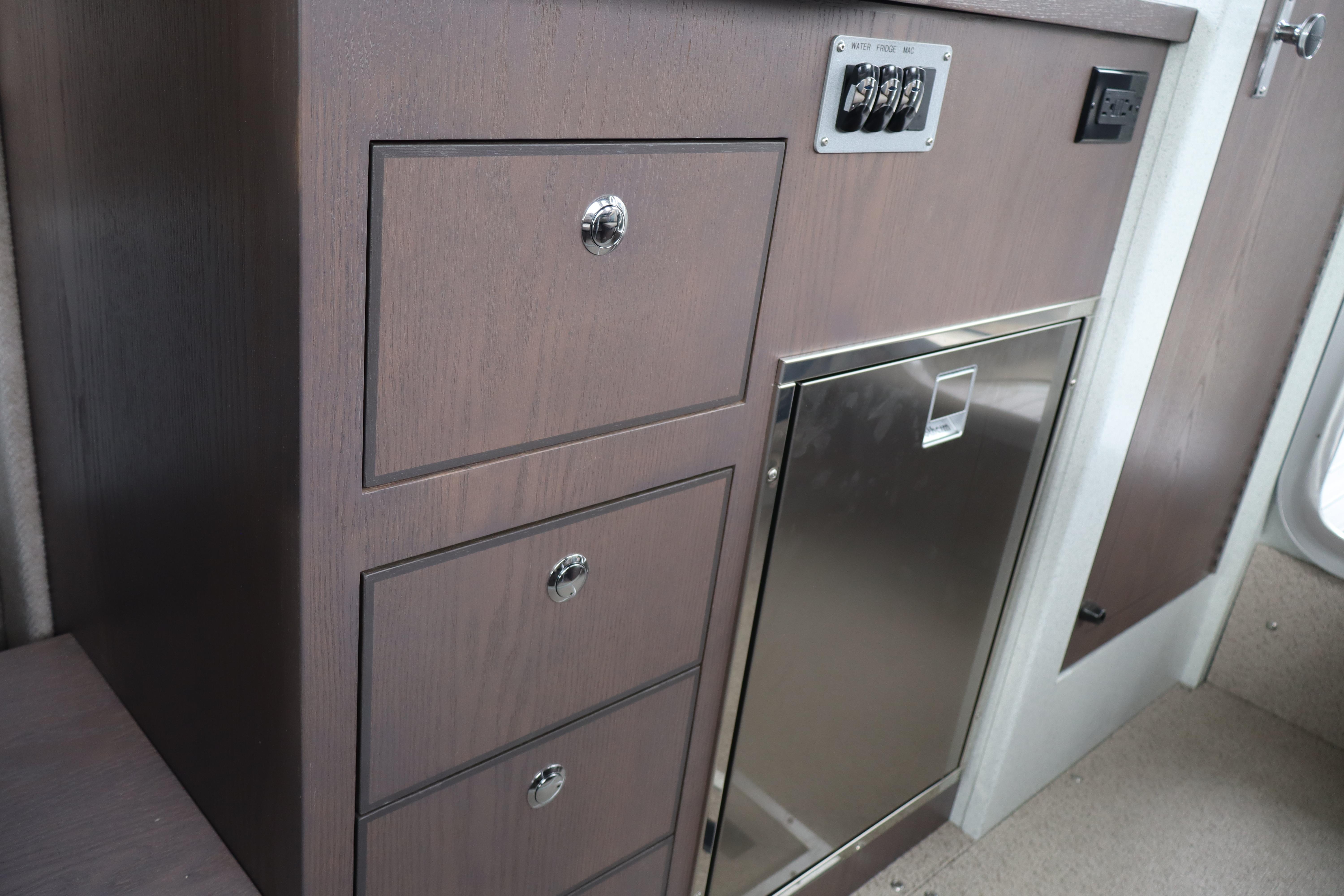 Interior of 2026 KingFisher 3025 XRS boat with wooden cabinetry and stainless steel panel.