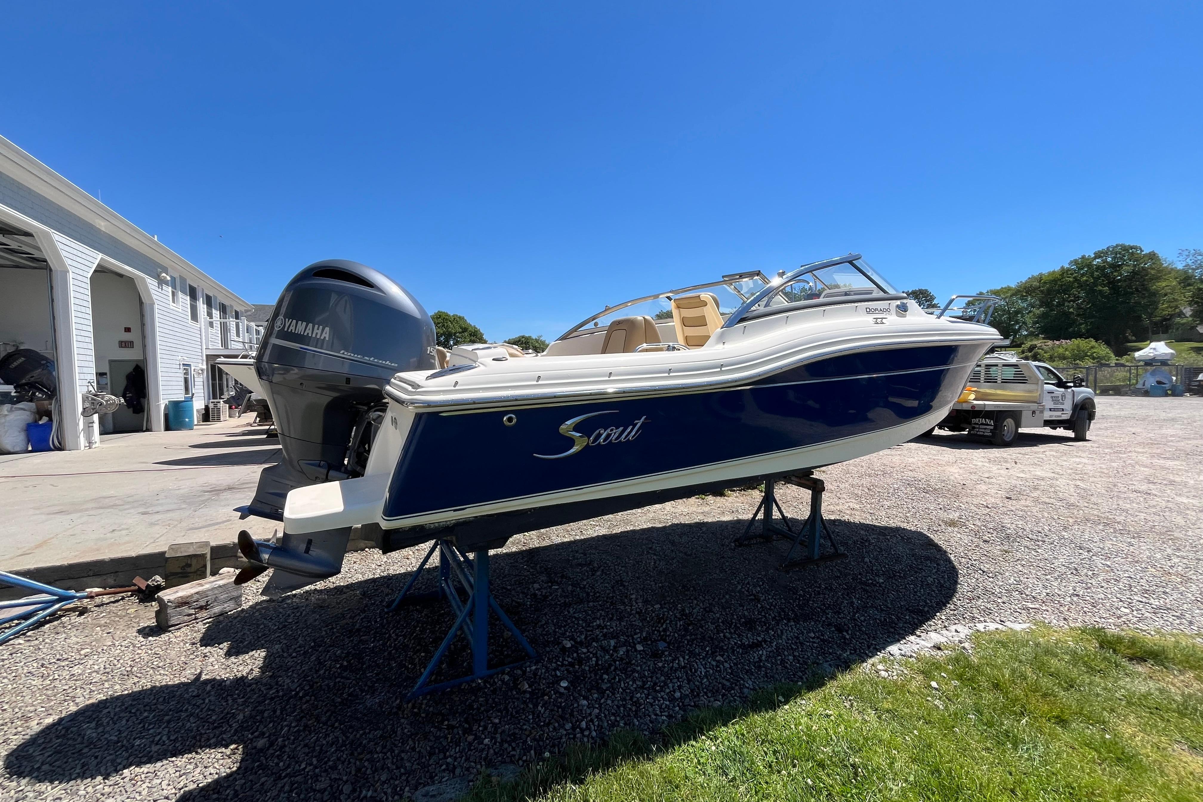 2017 Scout 210 Dorado boat with Yamaha engine on stands, outdoors under clear blue sky.