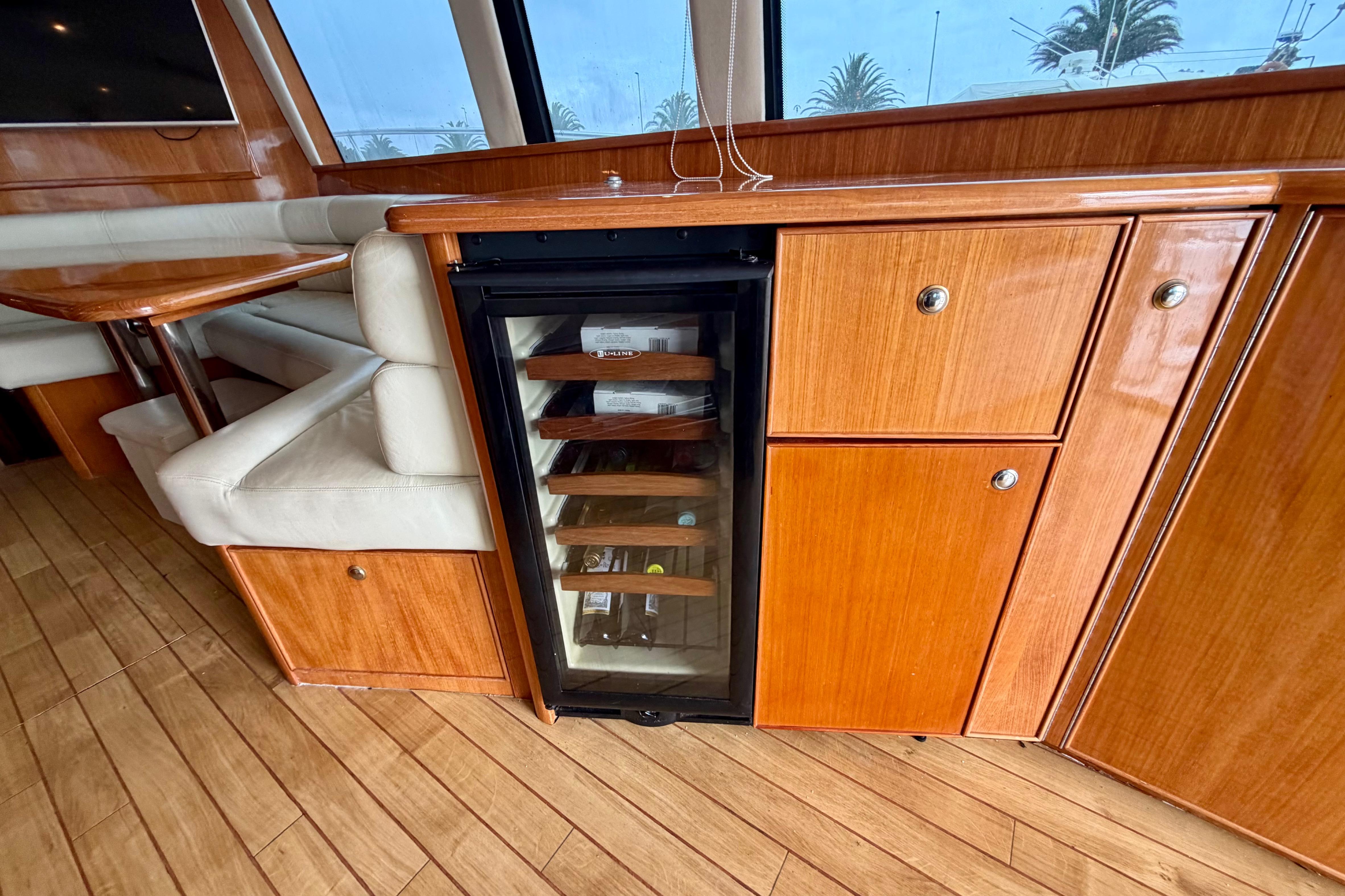 Luxurious interior of 2003 Riviera 60 Flybridge yacht with wood cabinetry and mini fridge.