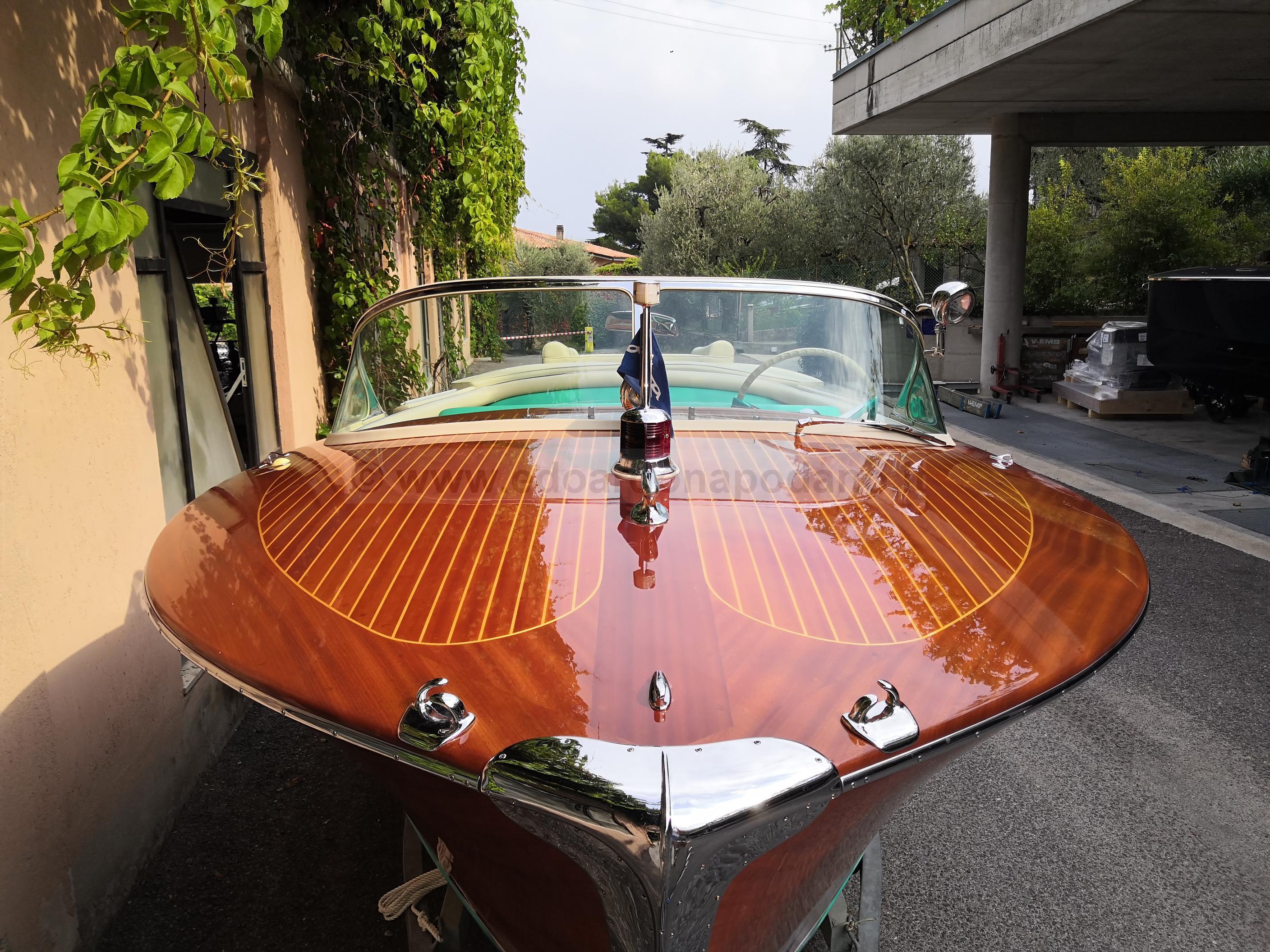 1963 Riva Ariston boat with polished wooden deck, parked outdoors.