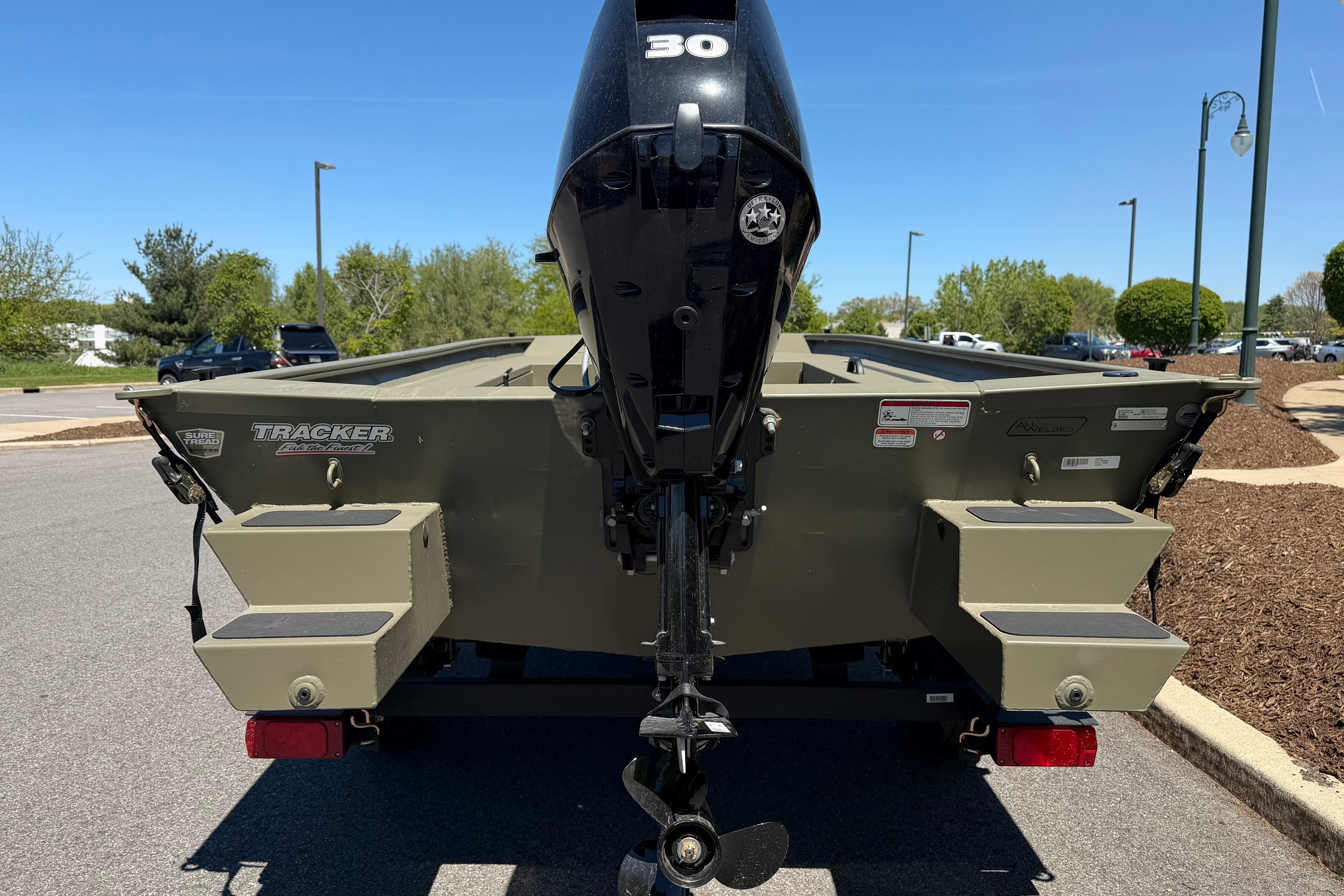 2026 Tracker Grizzly 1654 T Sportsman boat with outboard motor, parked outdoors.