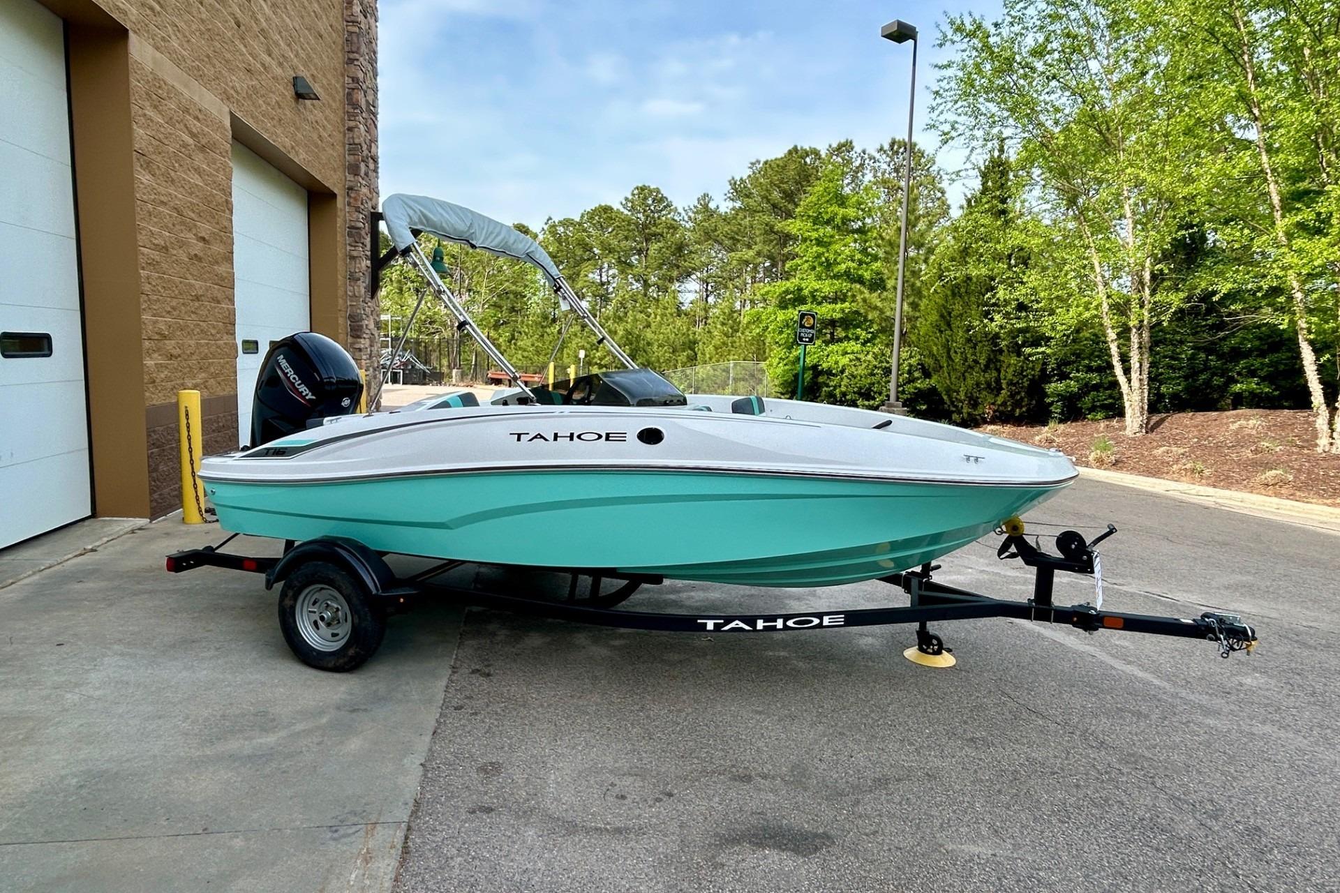 2026 Tahoe T16 boat on trailer, parked outdoors near a building and trees.