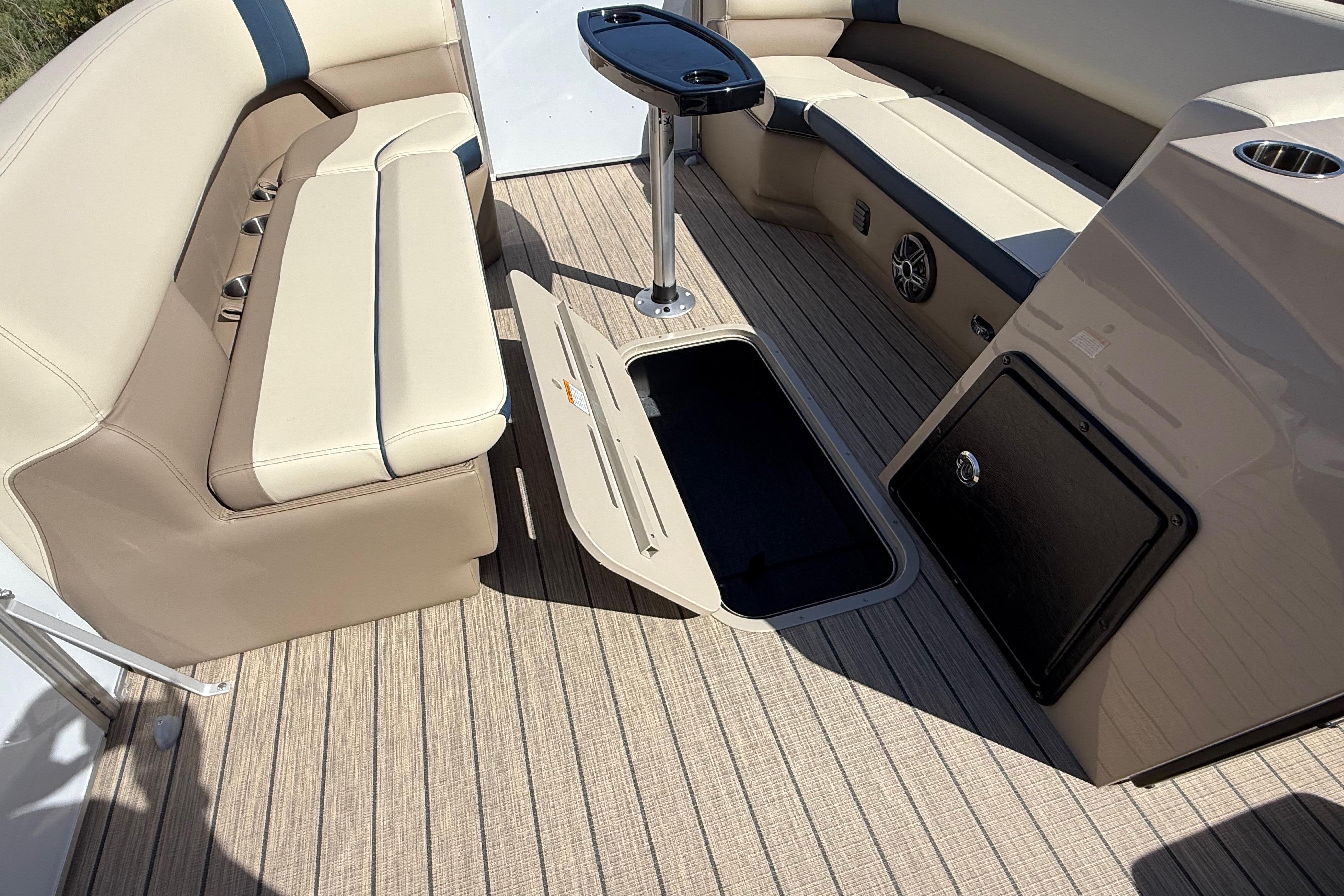 Interior of 2026 SunCatcher Select 322SL boat with beige seating and storage compartment.