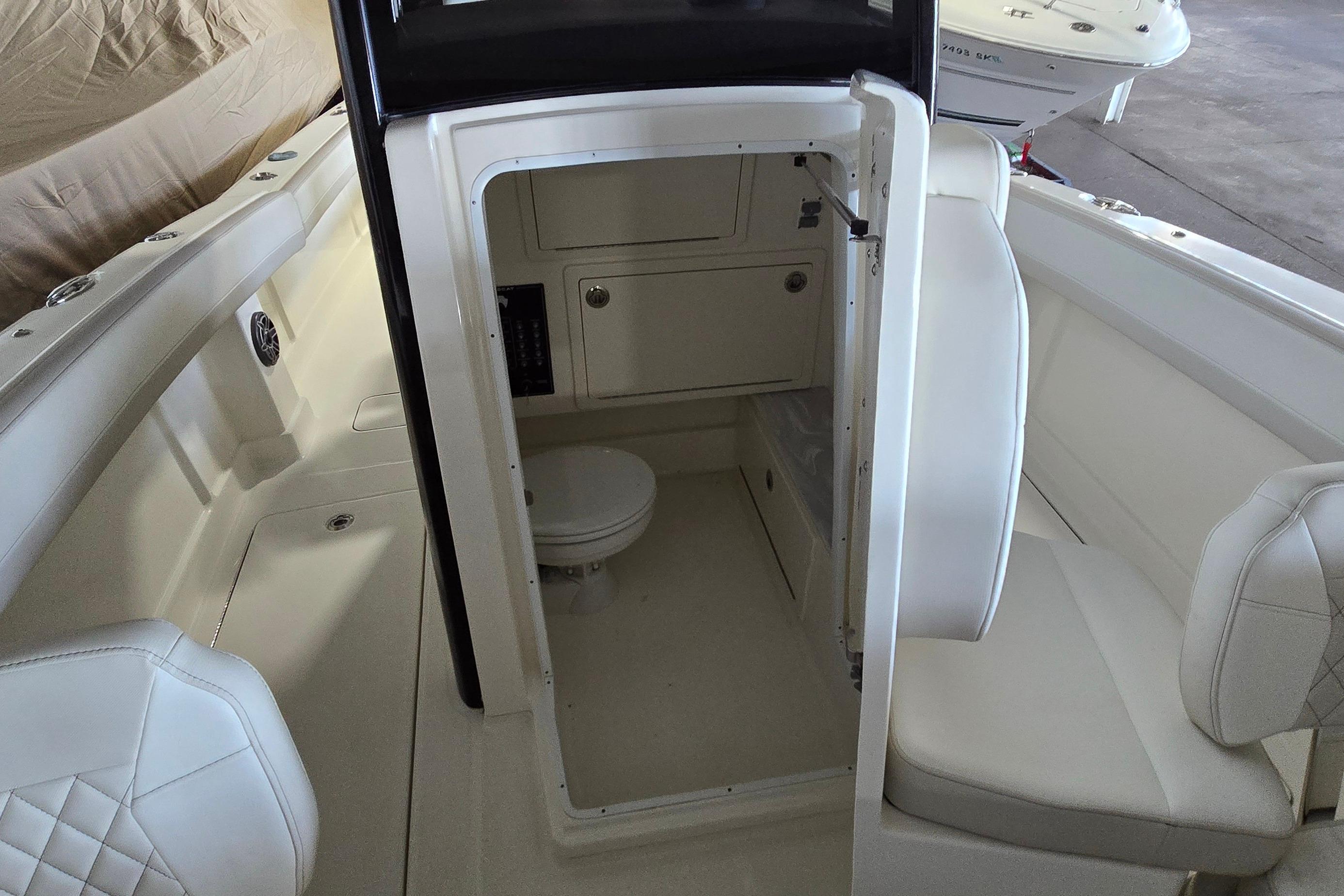 2024 WorldCat 280 CC-X boat interior with seating and compact restroom.