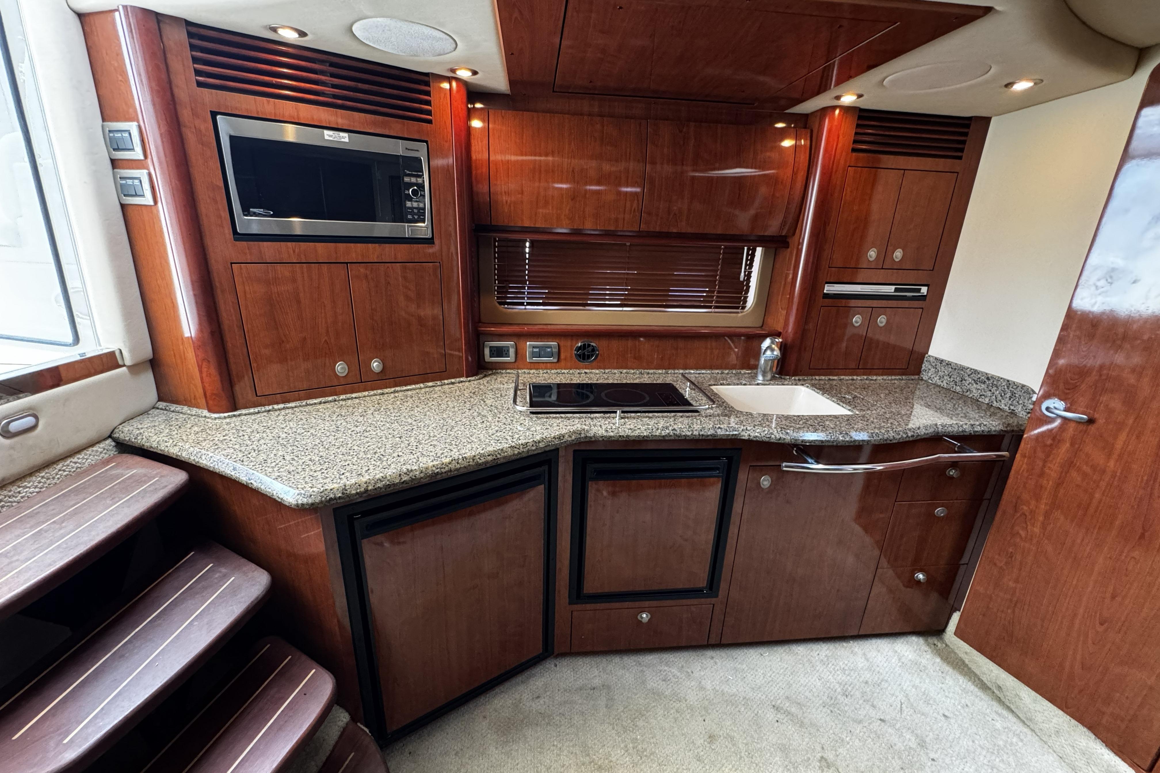 Luxurious 2006 Sea Ray 40 Sundancer yacht kitchen with wood cabinetry and modern appliances.