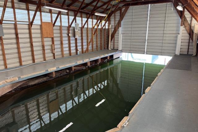 1960 custom boathouse interior with water channel and open garage door.