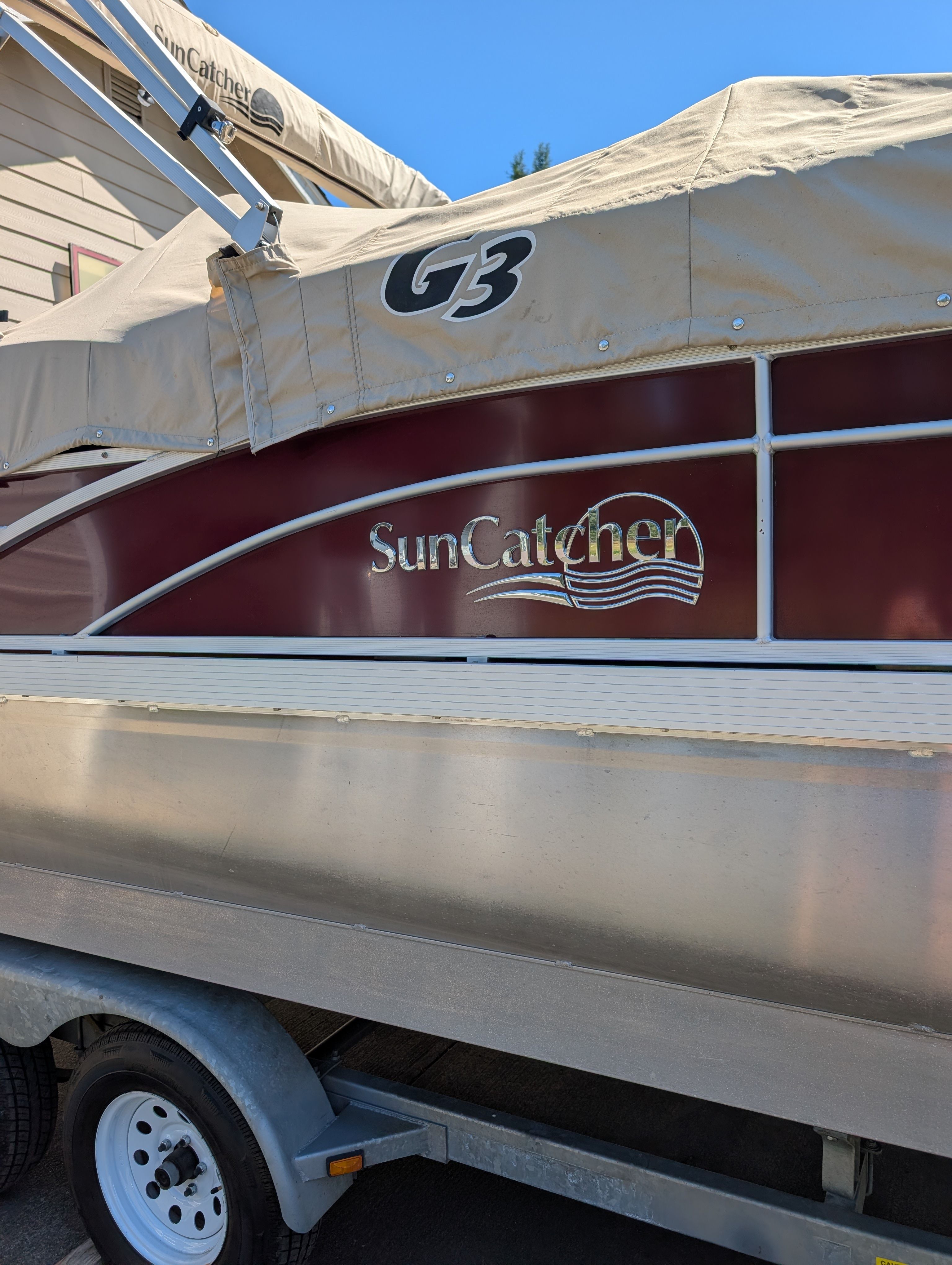 A 2016 SunCatcher V322 GX pontoon boat on a trailer, featuring a cover and branding.