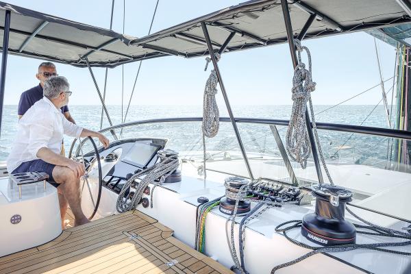 Two people navigating a 2025 Privilege Signature 650 yacht on open water.